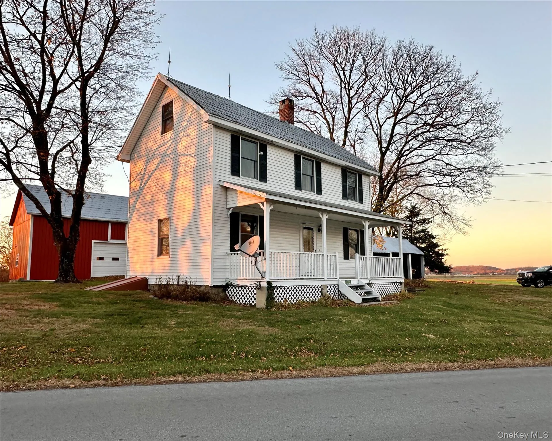 Farmhouse featuring a yard, a porch, and a chimney Farmhouse featuring a yard, a porch, and a chimney