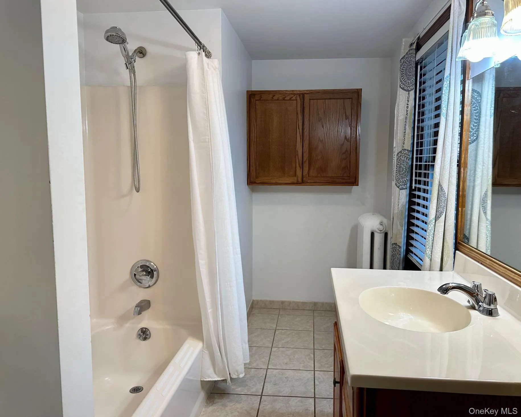 Bathroom featuring vanity, shower / tub combo with curtain, and light tile patterned flooring Bathroom featuring vanity, shower / tub combo with curtain, and light tile patterned flooring