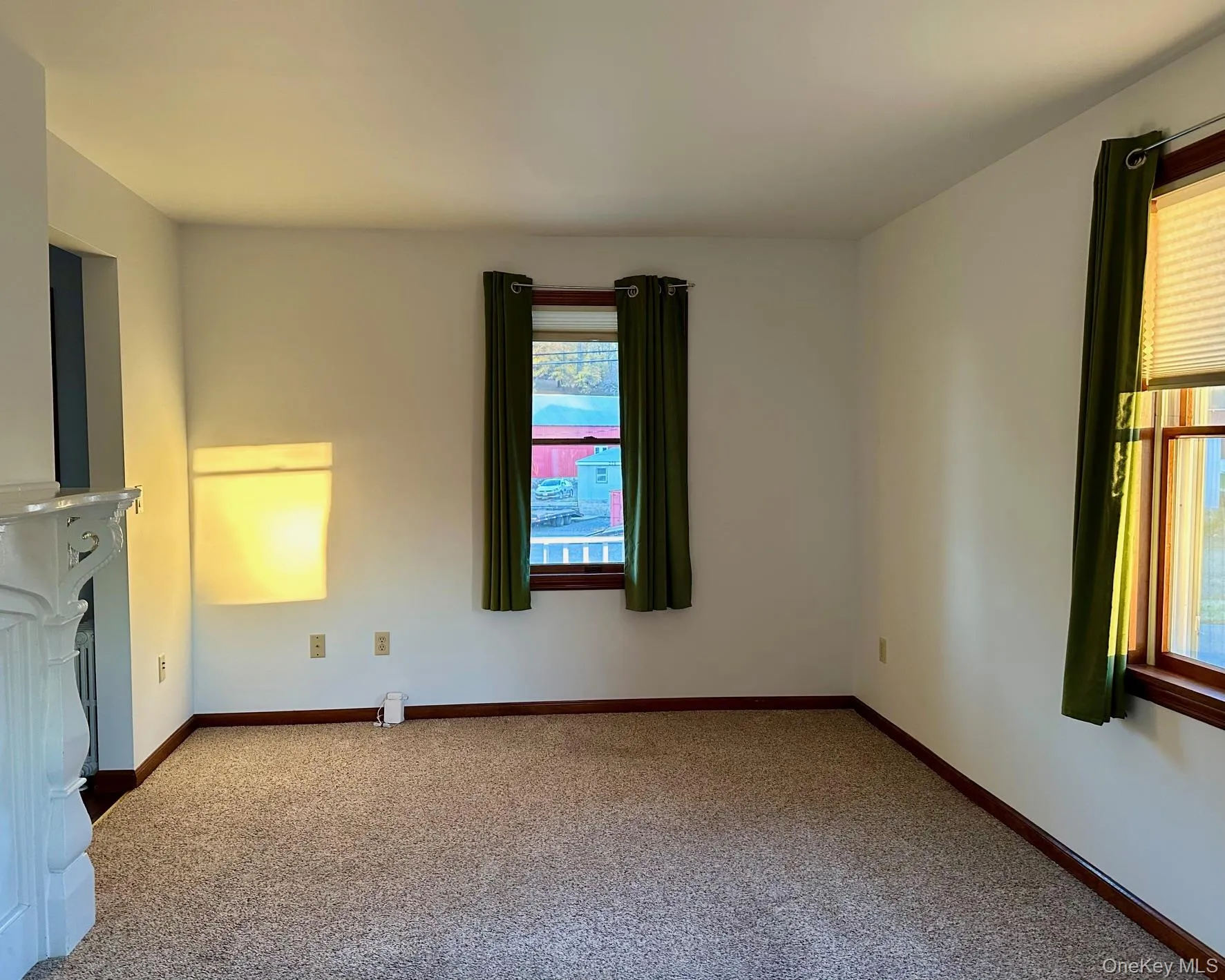Carpeted empty room with baseboards and a fireplace Carpeted empty room with baseboards and a fireplace
