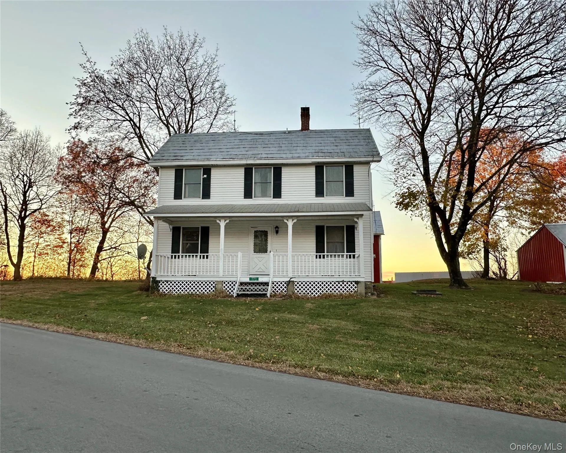 View of front of house featuring a porch, a chimney, and a front yard View of front of house featuring a porch, a chimney, and a front yard