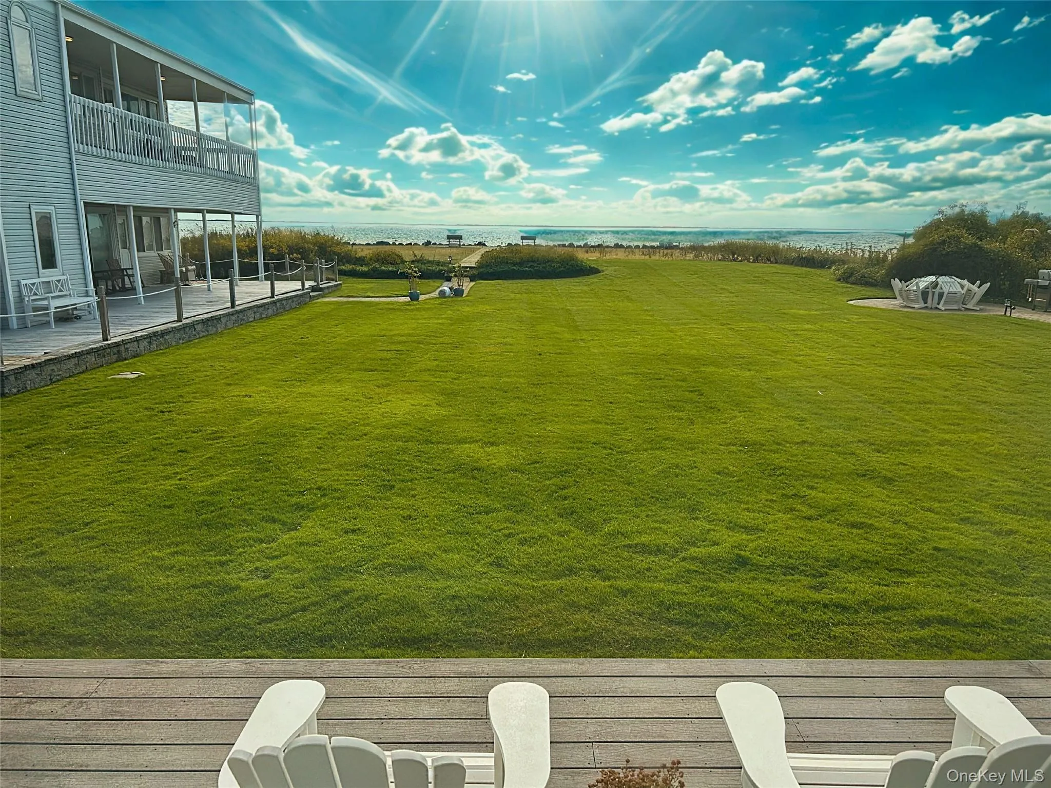 View of grassy yard featuring a water view and a balcony View of grassy yard featuring a water view and a balcony