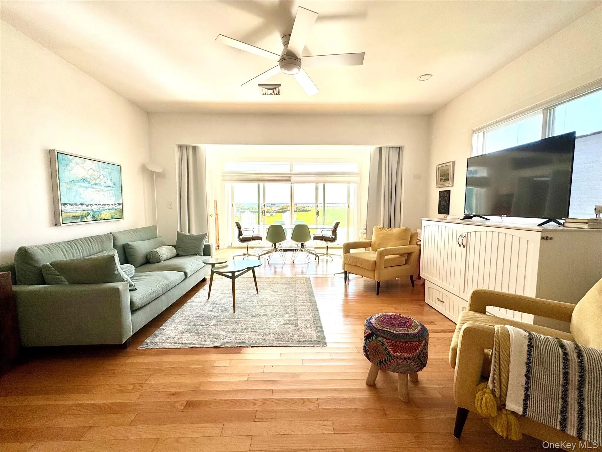 Living room featuring healthy amount of natural light, light wood-type flooring, and a ceiling fan Living room featuring healthy amount of natural light, light wood-type flooring, and a ceiling fan