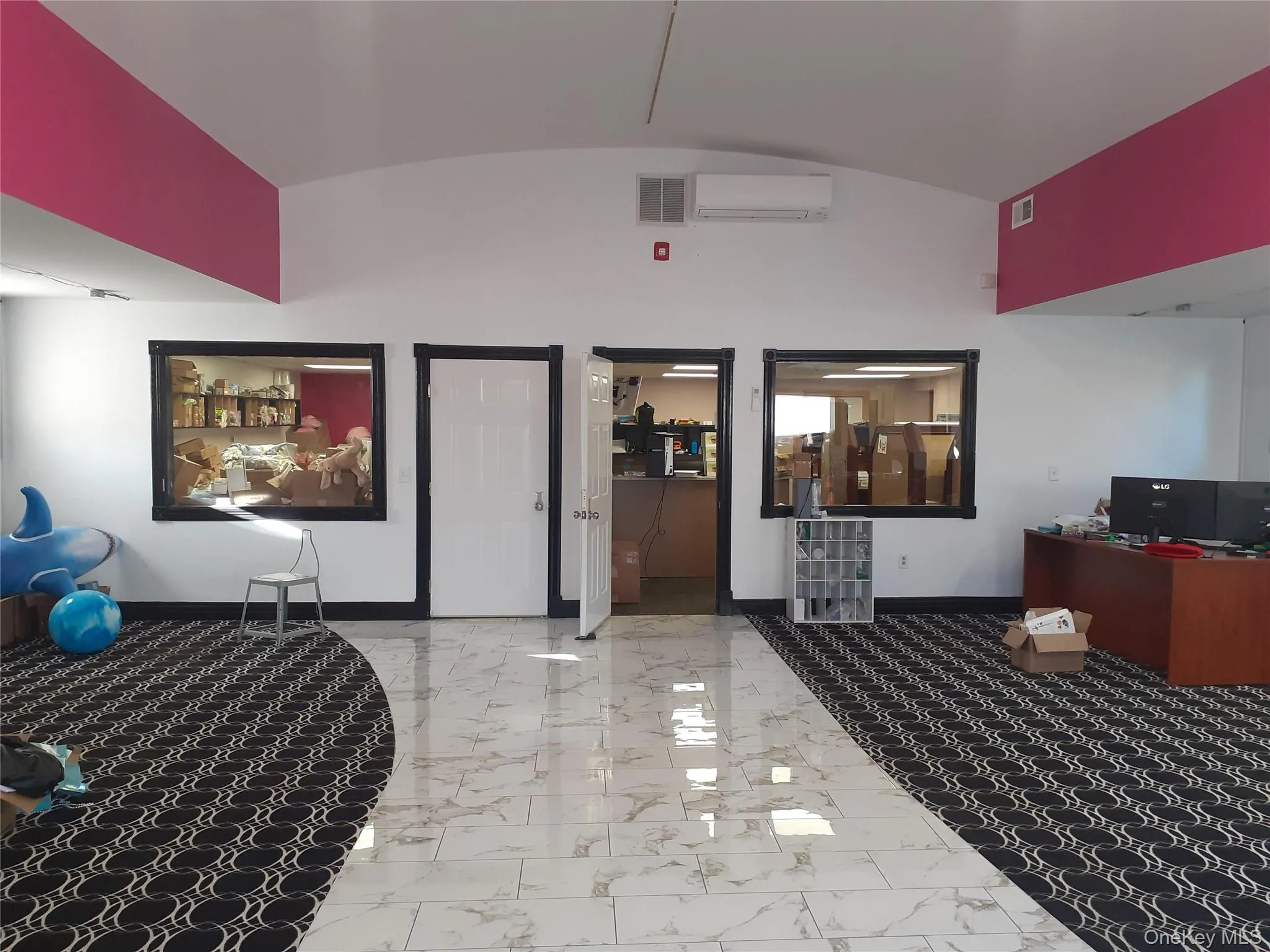 Bedroom featuring a desk, light marble finish flooring, vaulted ceiling, and an AC wall unit Bedroom featuring a desk, light marble finish flooring, vaulted ceiling, and an AC wall unit