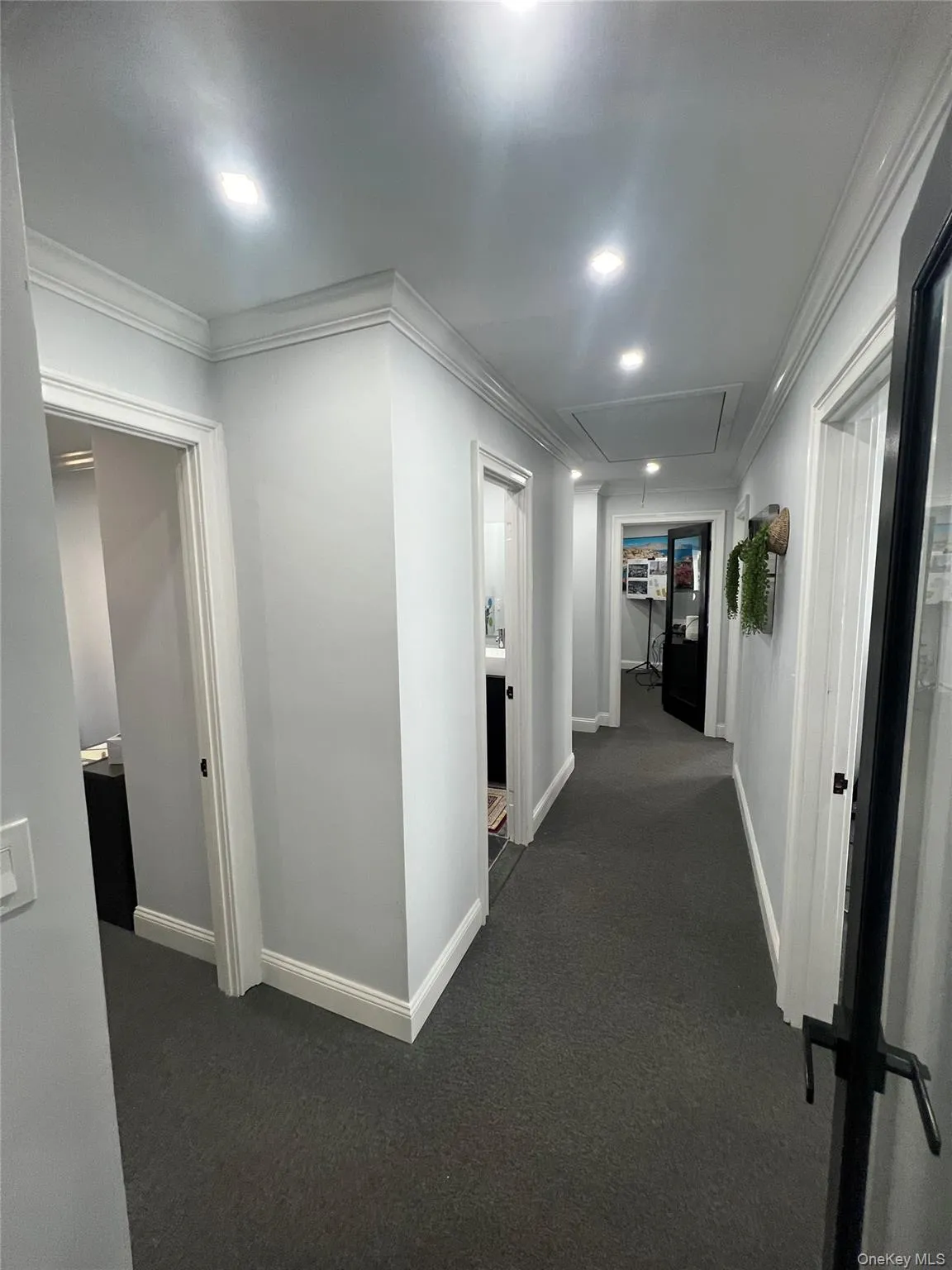 Hallway with crown molding, dark carpet, attic access, and recessed lighting Hallway with crown molding, dark carpet, attic access, and recessed lighting