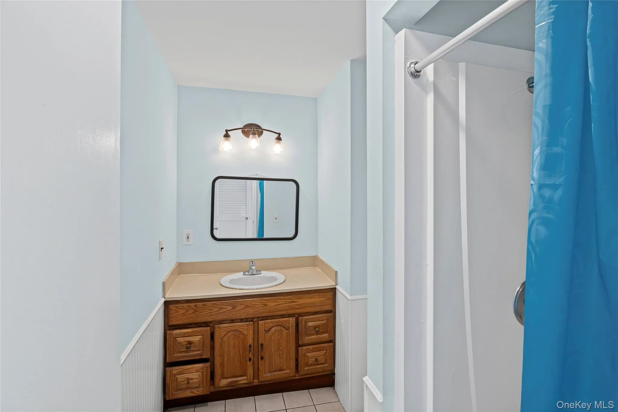 1st floor full bathroom with curtained shower, vanity, and light tile patterned floors 1st floor full bathroom with curtained shower, vanity, and light tile patterned floors