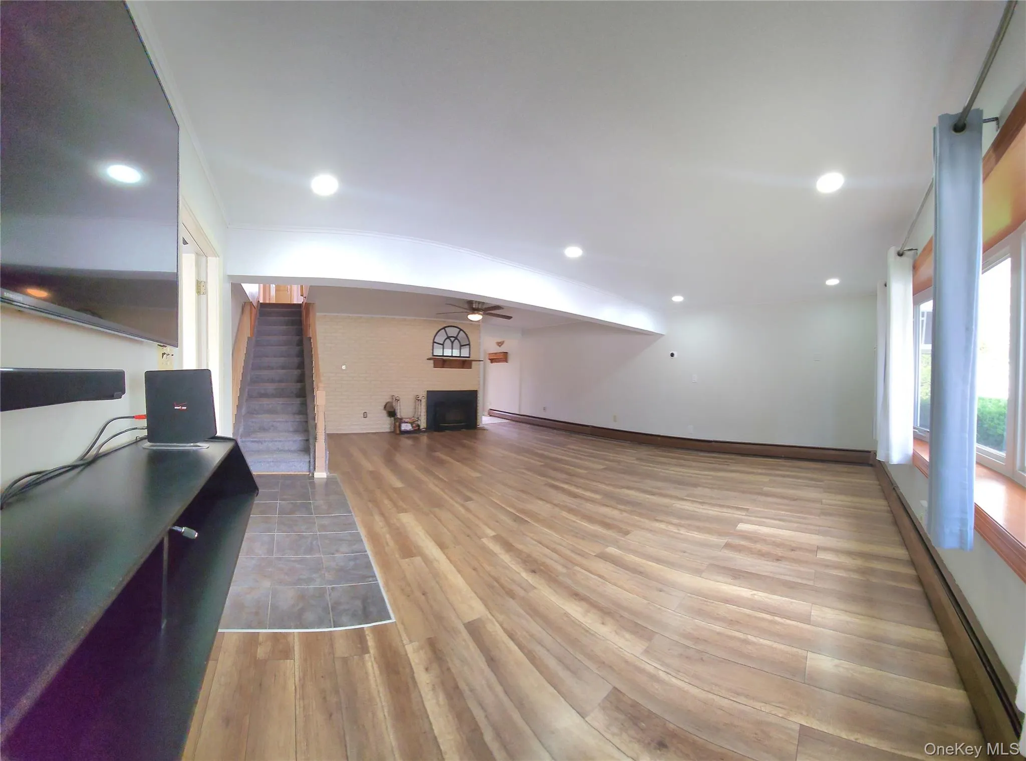 Living area featuring a fireplace, light wood finished floors, a baseboard radiator, ceiling fan, and recessed lighting Living area featuring a fireplace, light wood finished floors, a baseboard radiator, ceiling fan, and recessed lighting