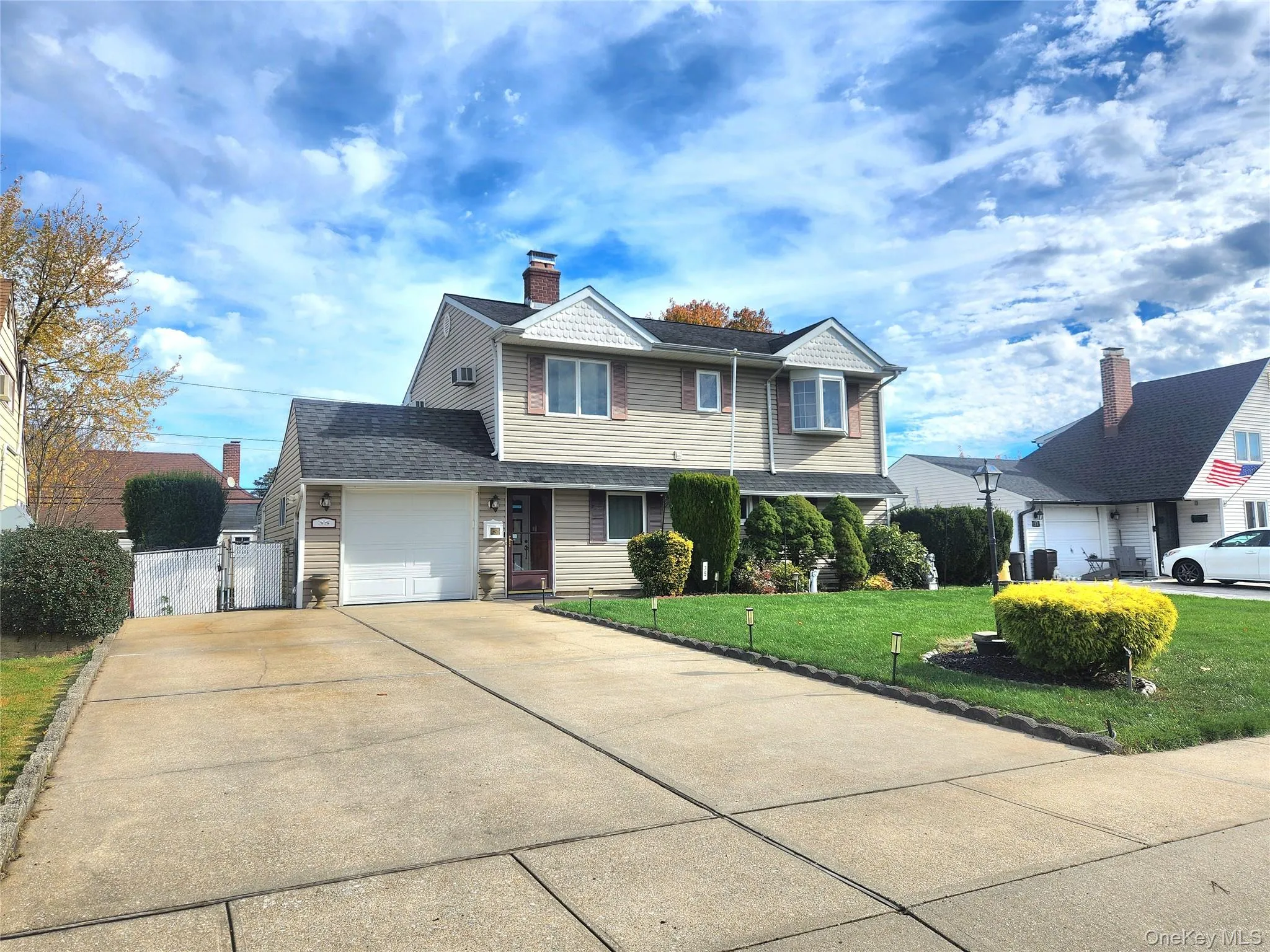 Traditional-style home featuring a gate, driveway, a shingled roof, a garage, and a chimney Traditional-style home featuring a gate, driveway, a shingled roof, a garage, and a chimney