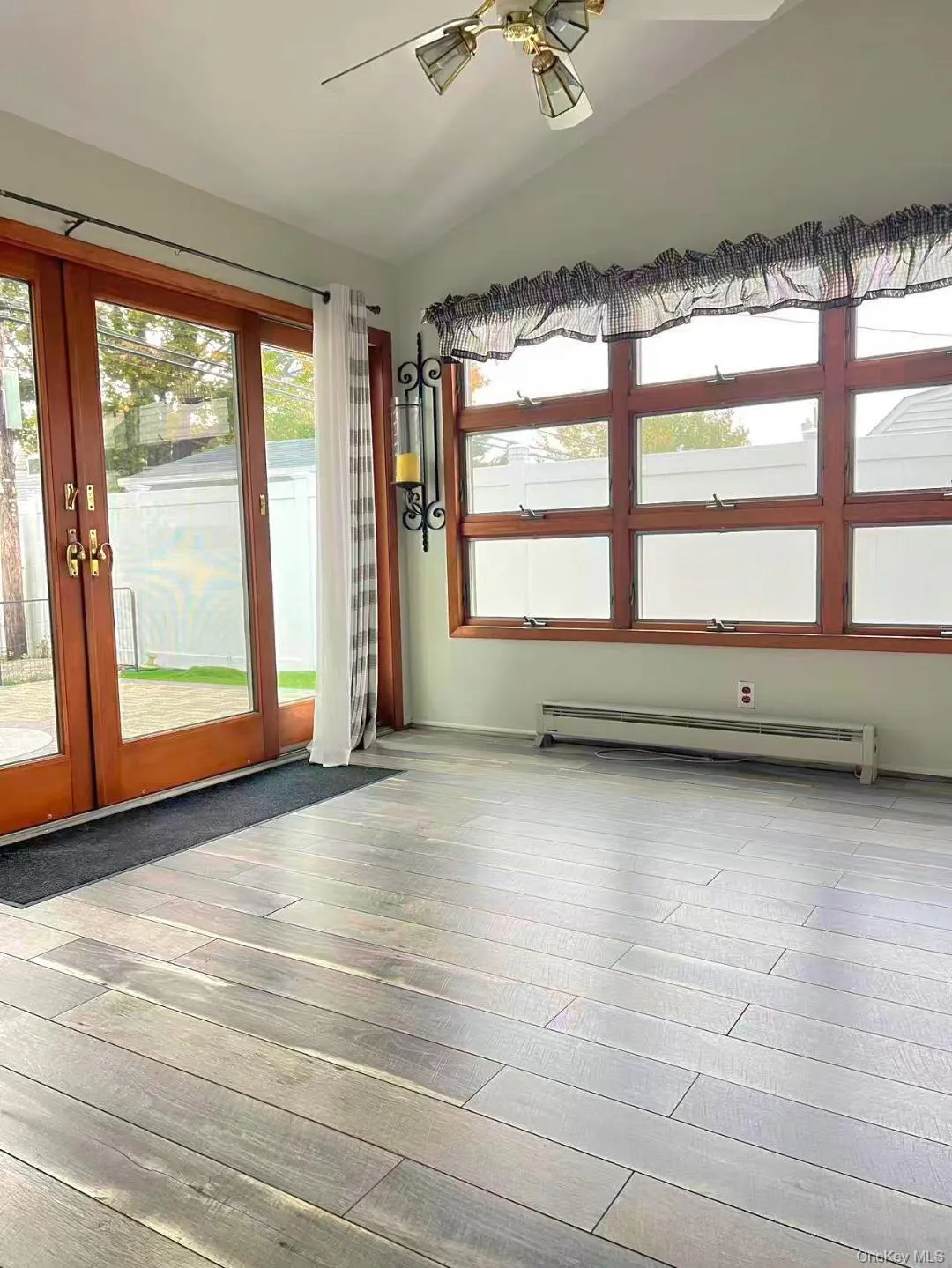 Unfurnished sunroom featuring lofted ceiling, baseboard heating, and french doors Unfurnished sunroom featuring lofted ceiling, baseboard heating, and french doors