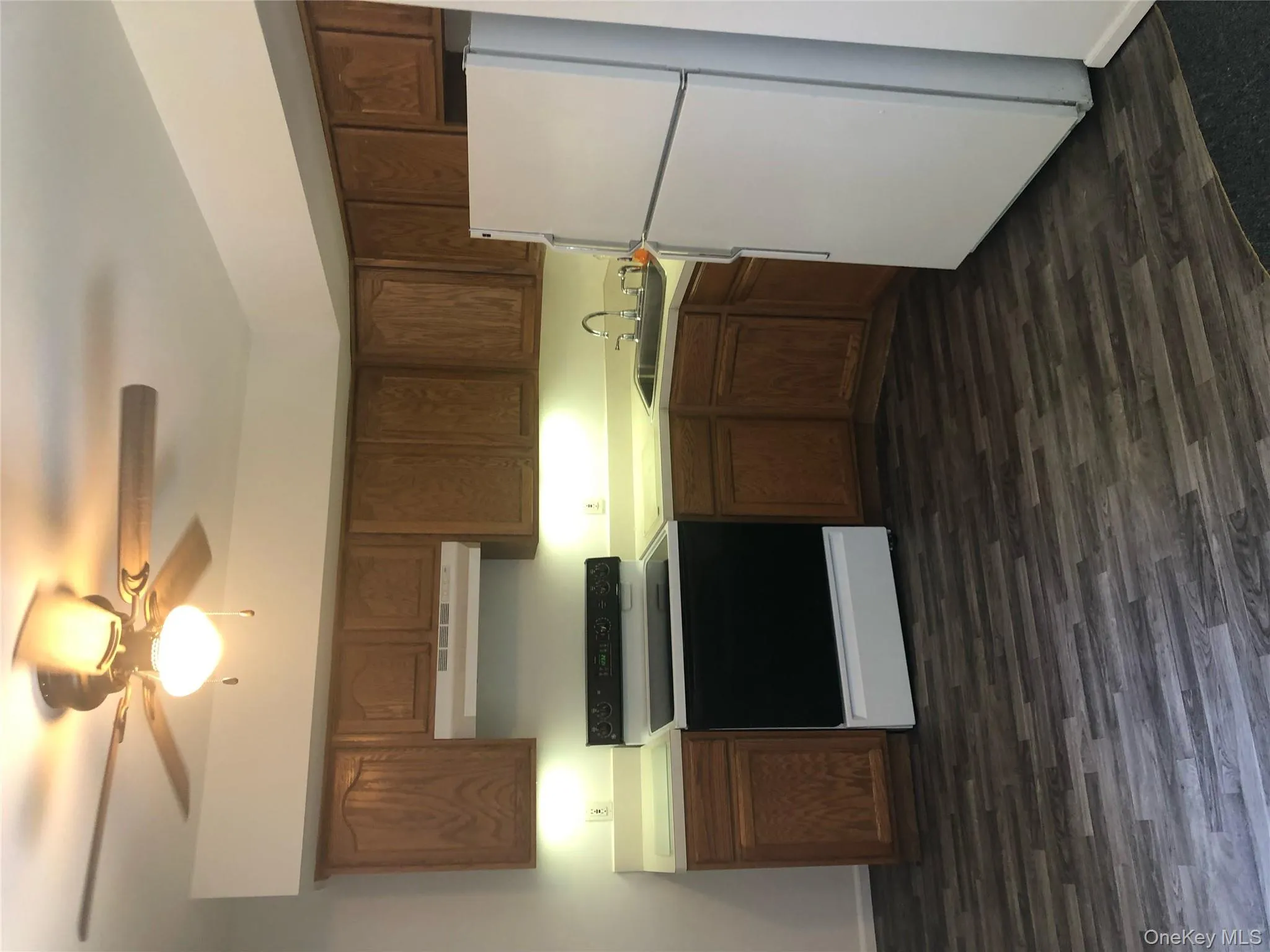 Kitchen featuring fridge, range, a ceiling fan, light countertops, and dark wood-style flooring Kitchen featuring fridge, range, a ceiling fan, light countertops, and dark wood-style flooring