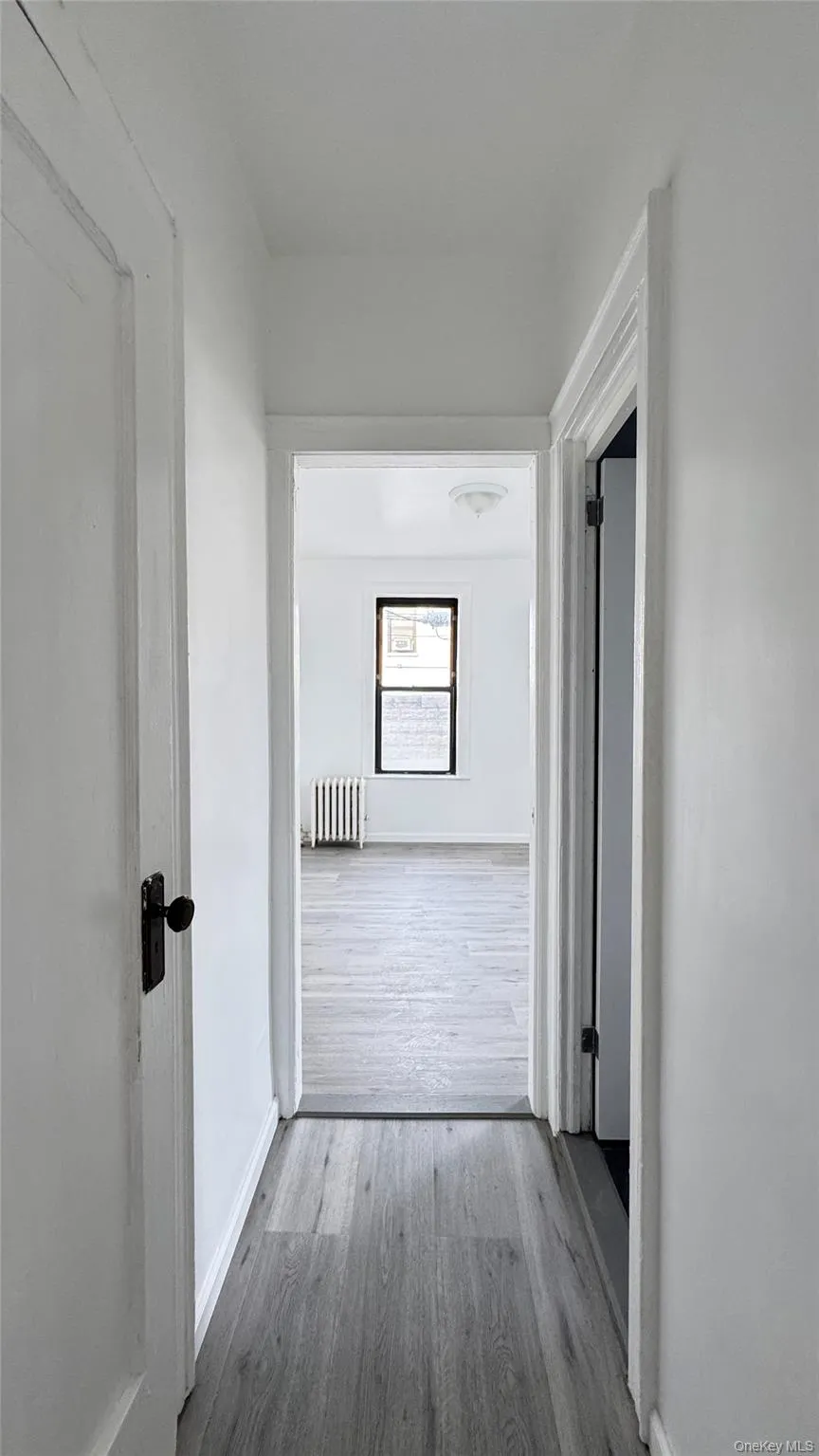 Hall featuring wood finished floors and radiator heating unit Hall featuring wood finished floors and radiator heating unit