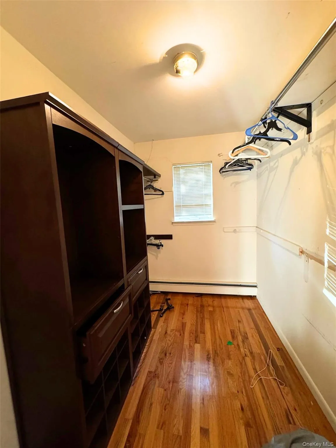 Walk in closet featuring light wood finished floors and baseboard heating Walk in closet featuring light wood finished floors and baseboard heating
