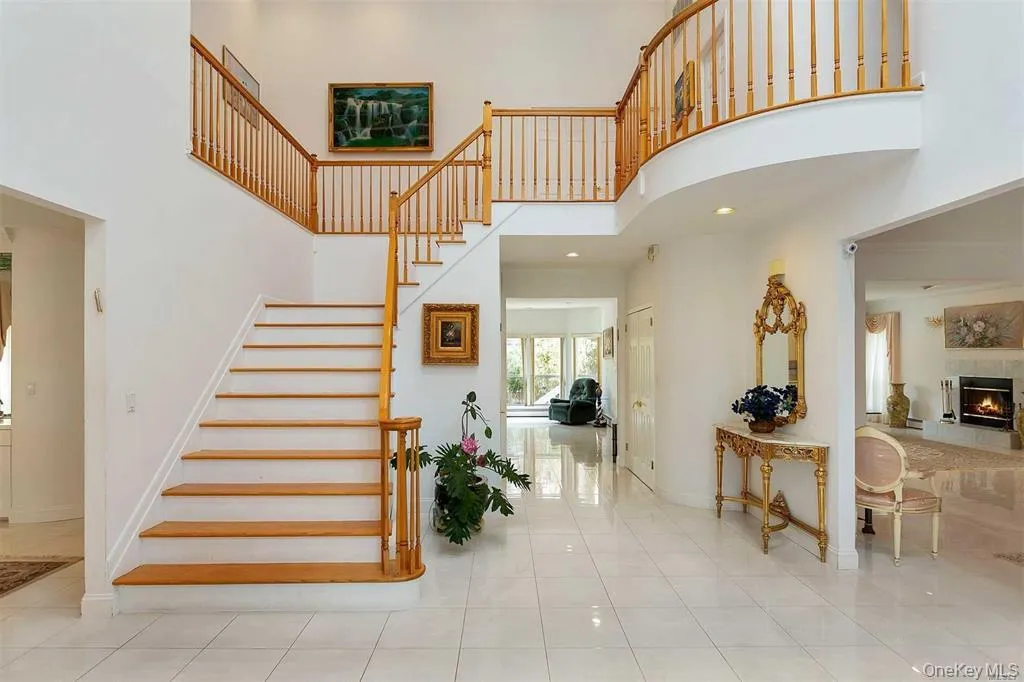Stairs with a towering ceiling, tile patterned flooring, a lit fireplace, and recessed lighting Stairs with a towering ceiling, tile patterned flooring, a lit fireplace, and recessed lighting