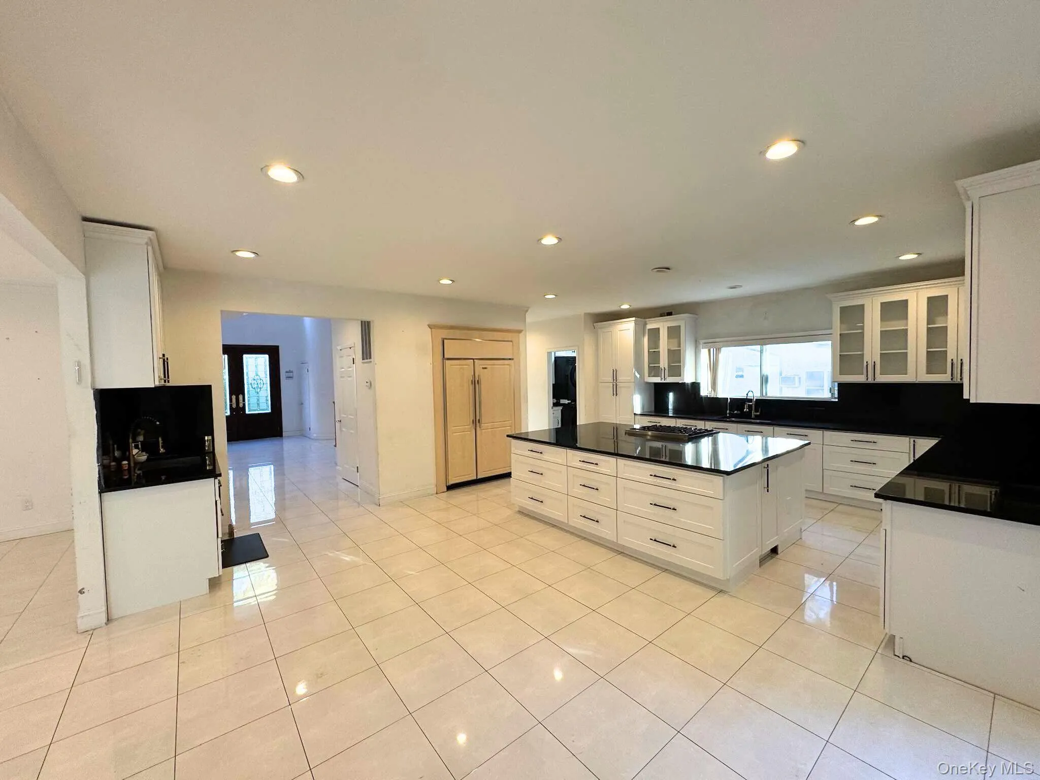 Kitchen featuring glass insert cabinets, recessed lighting, white cabinetry, light tile patterned flooring, and a kitchen island Kitchen featuring glass insert cabinets, recessed lighting, white cabinetry, light tile patterned flooring, and a kitchen island