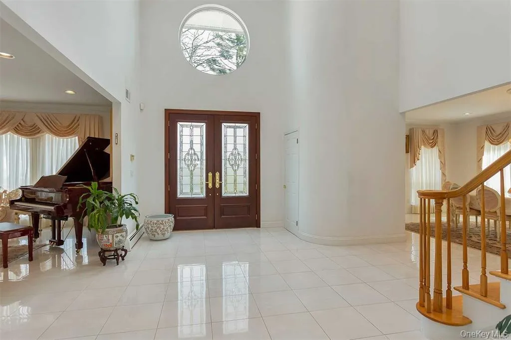 Entrance foyer featuring french doors, a high ceiling, light tile patterned floors, recessed lighting, and stairway Entrance foyer featuring french doors, a high ceiling, light tile patterned floors, recessed lighting, and stairway