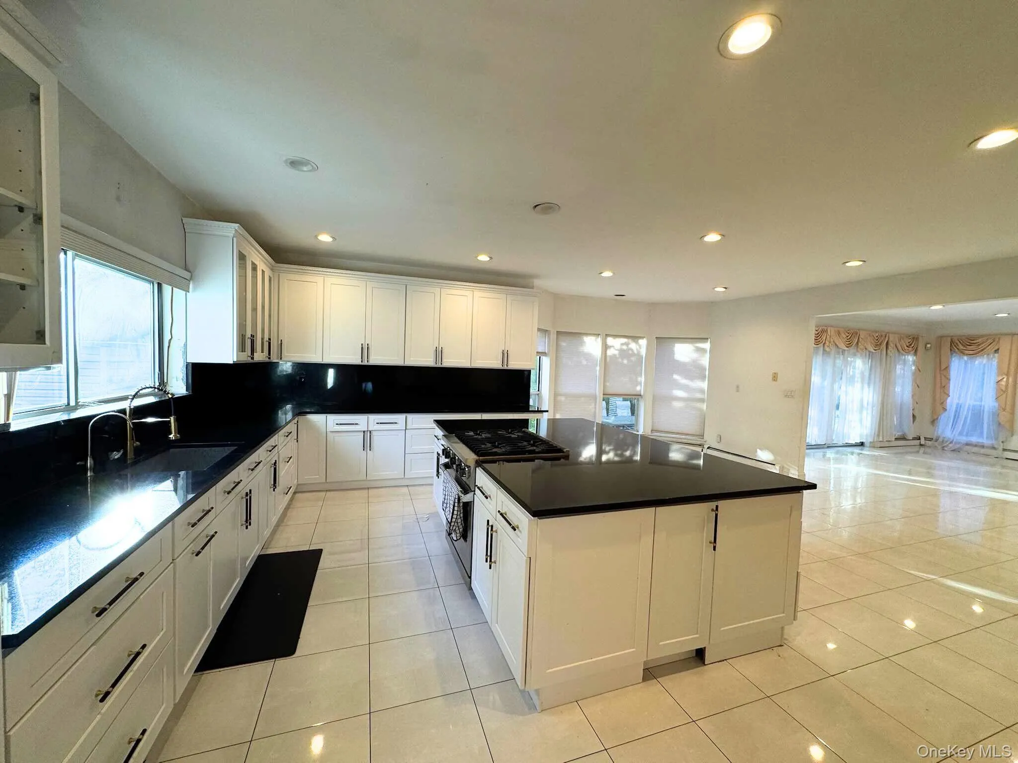 Kitchen featuring healthy amount of natural light, a kitchen island, gas range, recessed lighting, and light tile patterned floors Kitchen featuring healthy amount of natural light, a kitchen island, gas range, recessed lighting, and light tile patterned floors