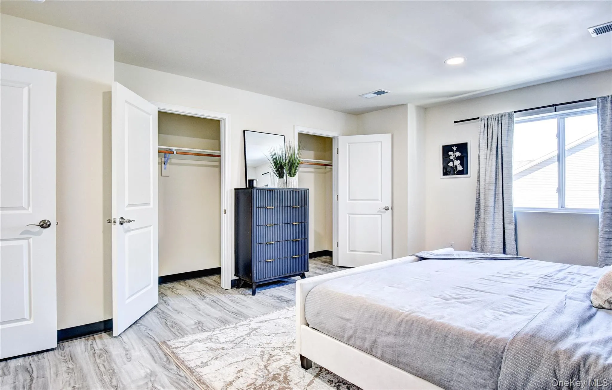 Bedroom featuring two closets and light hardwood / wood-style flooring Bedroom featuring two closets and light hardwood / wood-style flooring
