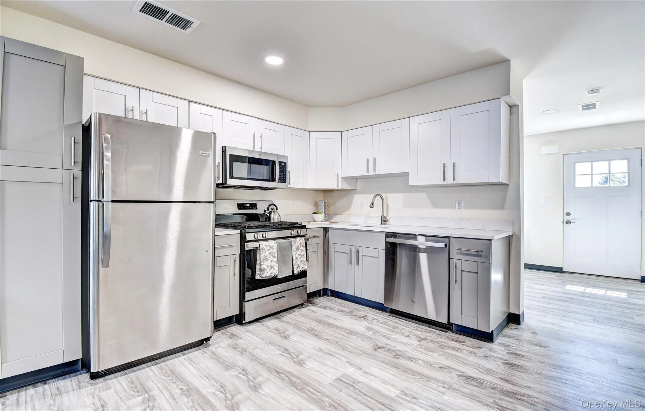 Kitchen with appliances with stainless steel finishes, gray cabinetry, light hardwood / wood-style floors, and sink Kitchen with appliances with stainless steel finishes, gray cabinetry, light hardwood / wood-style floors, and sink
