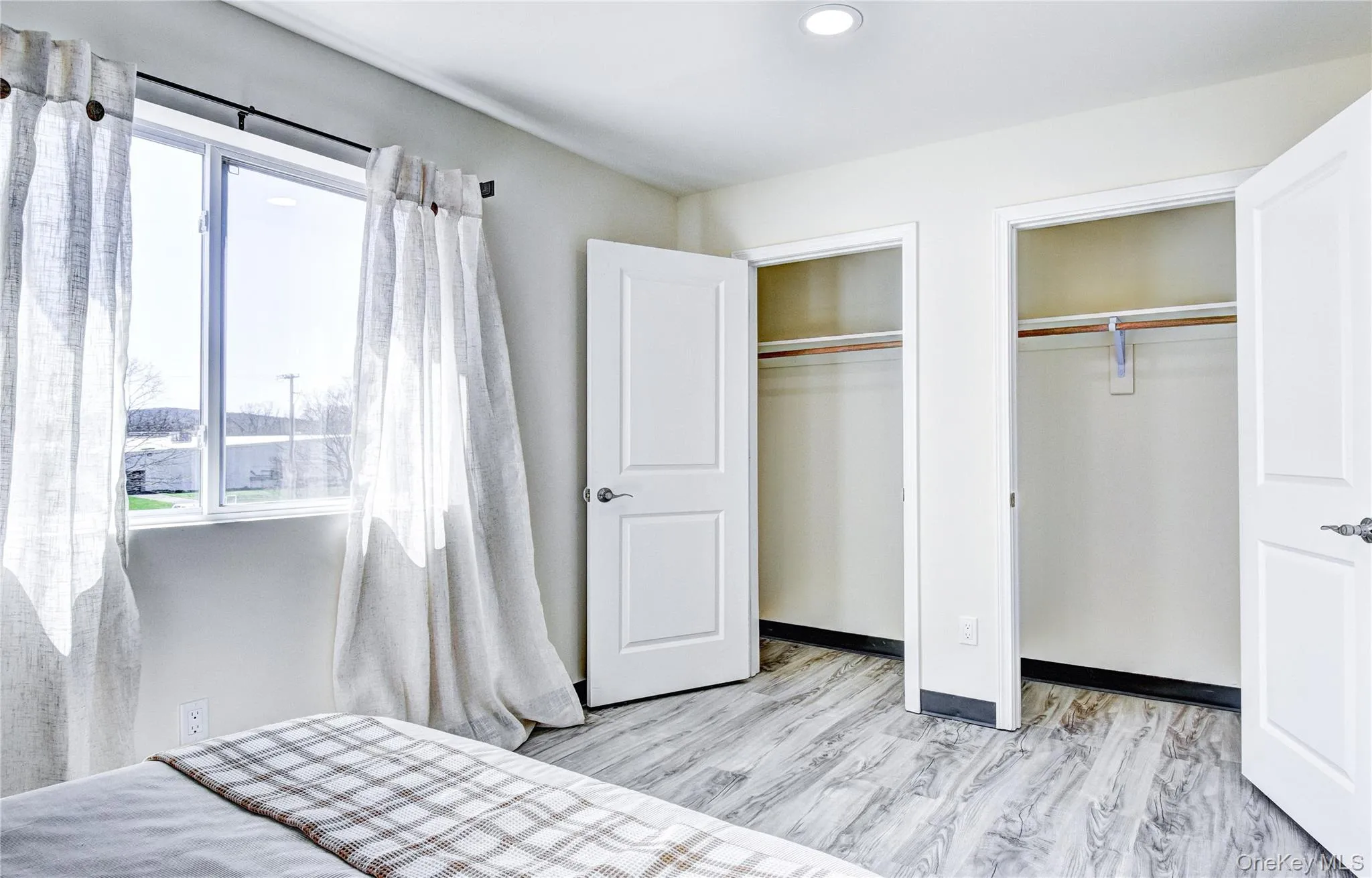 Bedroom with multiple closets and light hardwood / wood-style floors Bedroom with multiple closets and light hardwood / wood-style floors