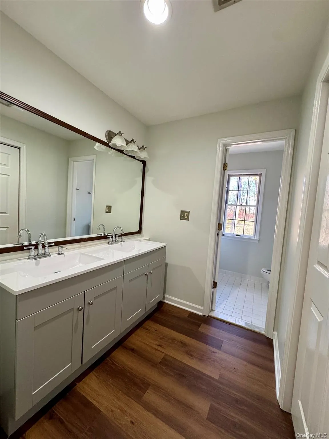 Bathroom featuring double vanity and dark wood-type flooring Bathroom featuring double vanity and dark wood-type flooring