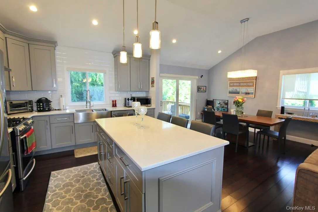 Kitchen featuring gray cabinets, decorative backsplash, lofted ceiling, appliances with stainless steel finishes, and dark wood-type flooring Kitchen featuring gray cabinets, decorative backsplash, lofted ceiling, appliances with stainless steel finishes, and dark wood-type flooring