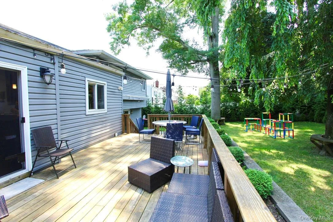 Deck with a lawn, outdoor dining space, and a playground Deck with a lawn, outdoor dining space, and a playground