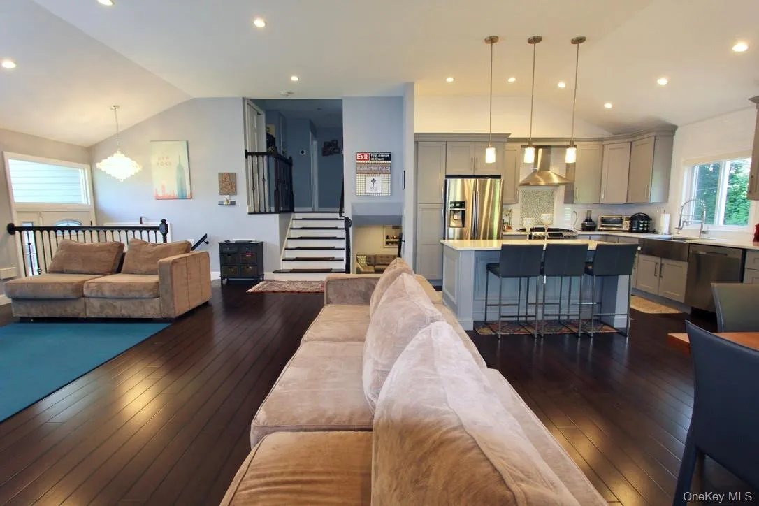 Living area with lofted ceiling, stairway, dark wood-style flooring, recessed lighting, and a chandelier Living area with lofted ceiling, stairway, dark wood-style flooring, recessed lighting, and a chandelier