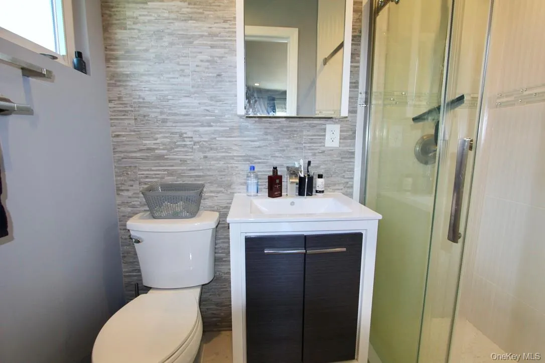 Full bath featuring vanity, a shower stall, decorative backsplash, and tile walls Full bath featuring vanity, a shower stall, decorative backsplash, and tile walls