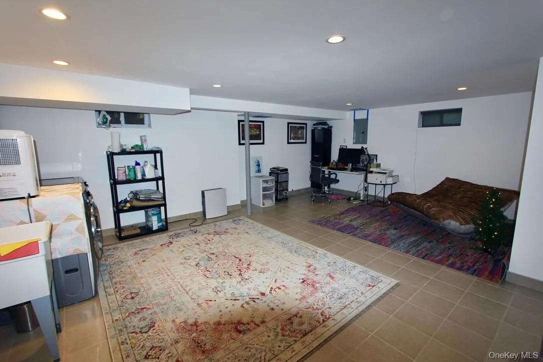 Living room featuring an office area, recessed lighting, light tile patterned flooring, and electric panel Living room featuring an office area, recessed lighting, light tile patterned flooring, and electric panel