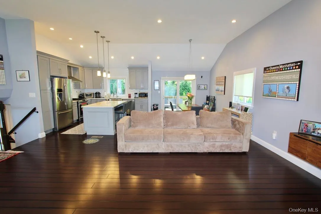 Living area featuring lofted ceiling, dark wood-style floors, and recessed lighting Living area featuring lofted ceiling, dark wood-style floors, and recessed lighting