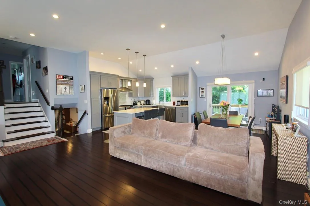 Living room with lofted ceiling, stairs, recessed lighting, and dark wood-style floors Living room with lofted ceiling, stairs, recessed lighting, and dark wood-style floors