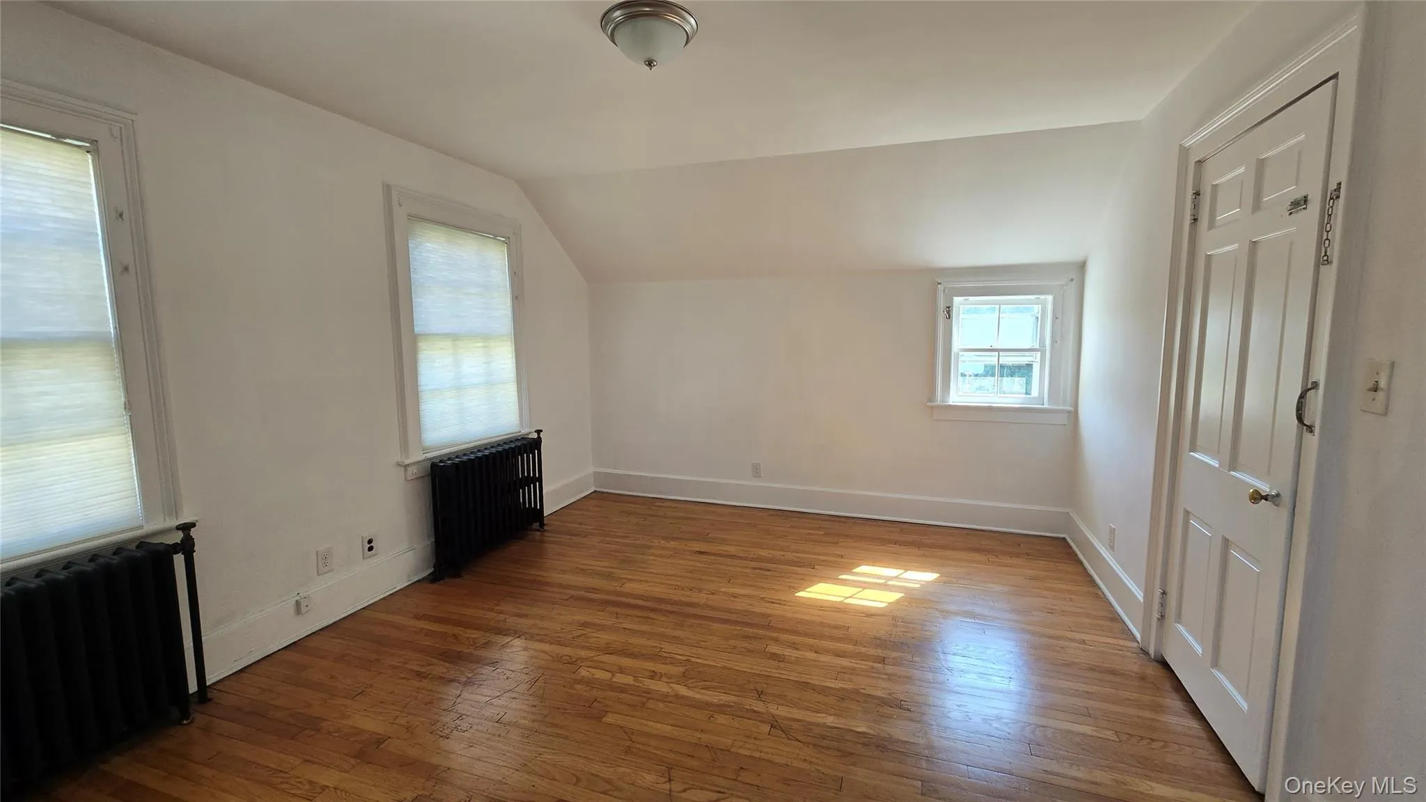 Bonus room with lofted ceiling, radiator, and wood-type flooring Bonus room with lofted ceiling, radiator, and wood-type flooring