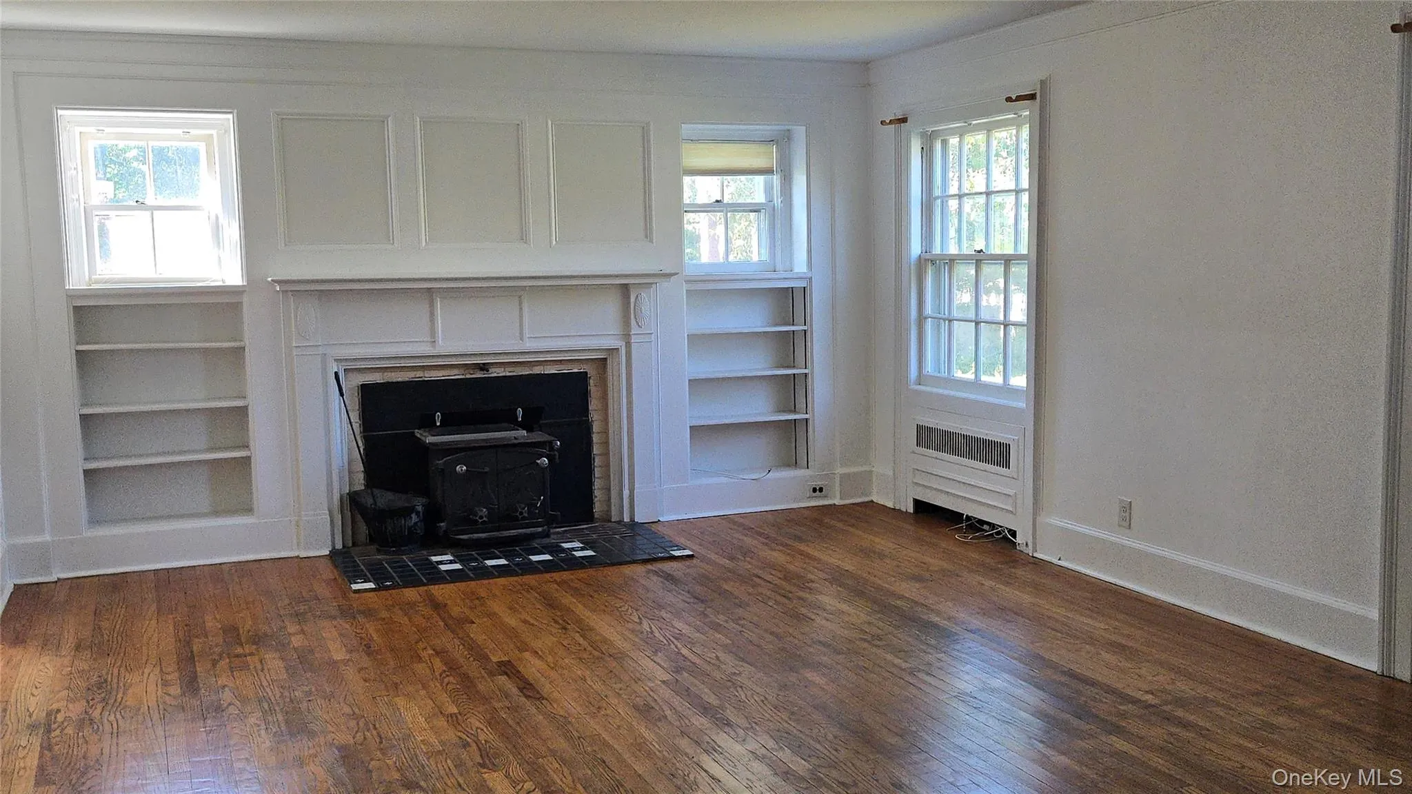 Unfurnished living room with dark wood-style floors and a wood stove Unfurnished living room with dark wood-style floors and a wood stove