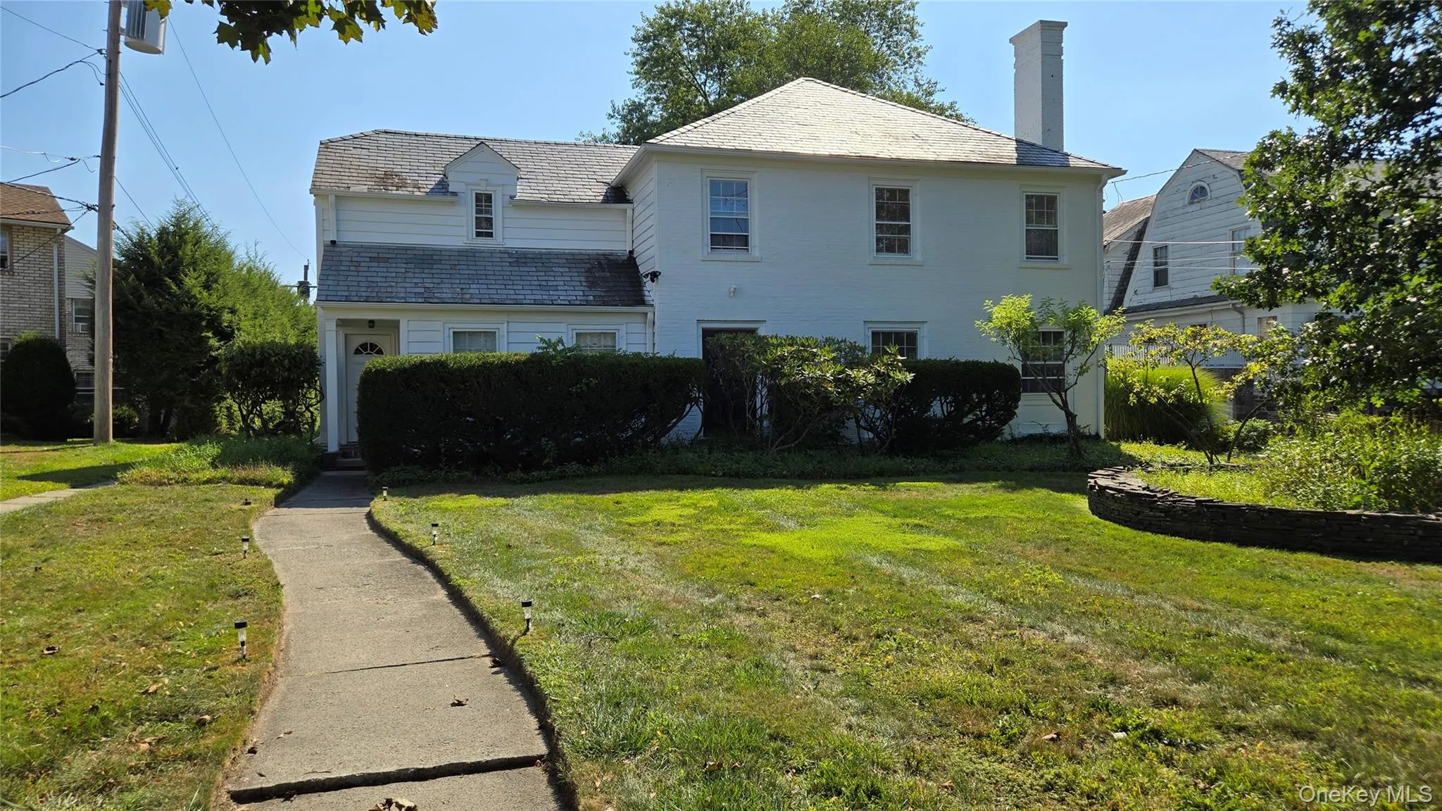 View of front facade with a high end roof, a front lawn, and a chimney View of front facade with a high end roof, a front lawn, and a chimney