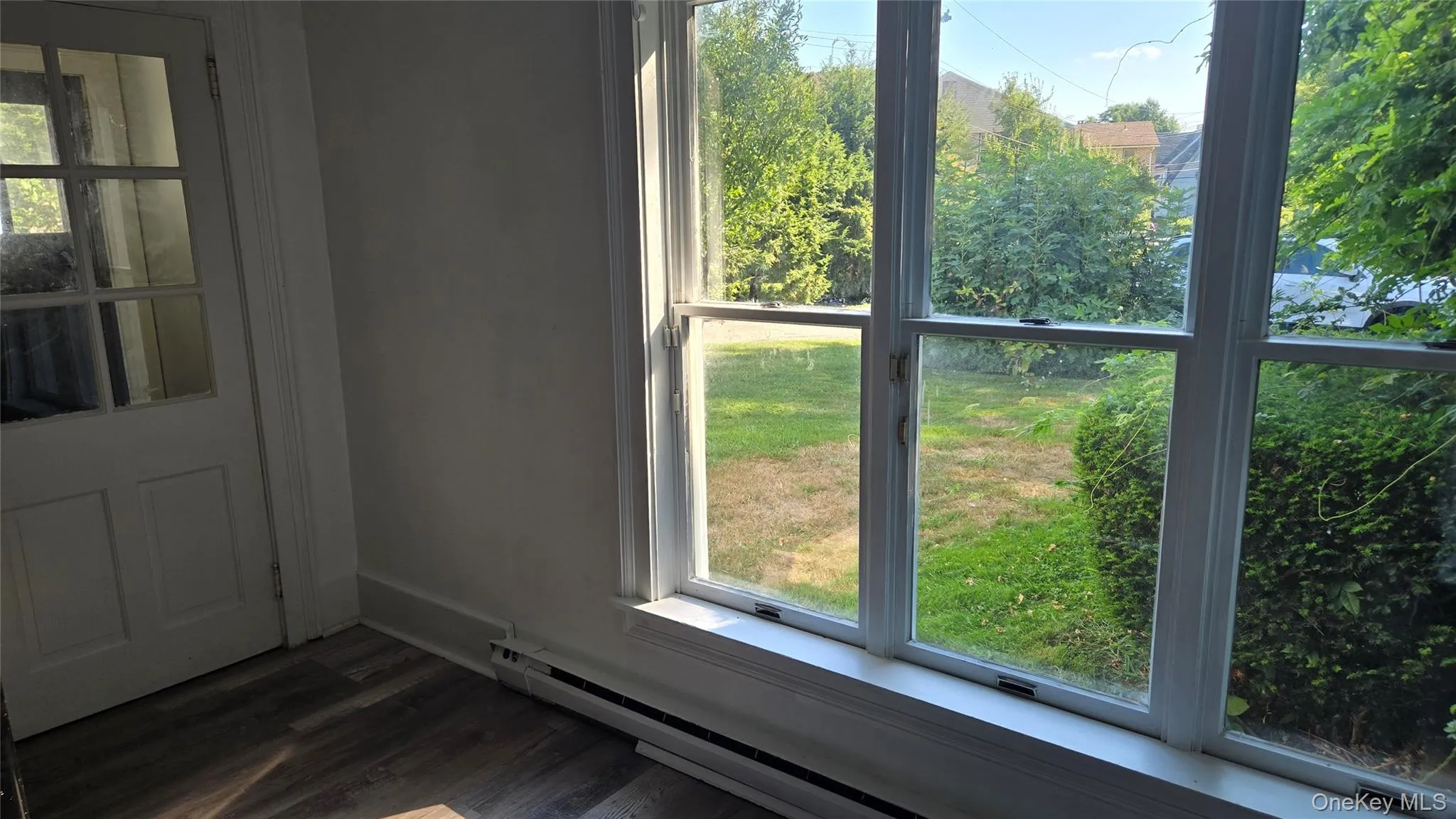 Doorway to outside with wood finished floors and a baseboard radiator Doorway to outside with wood finished floors and a baseboard radiator