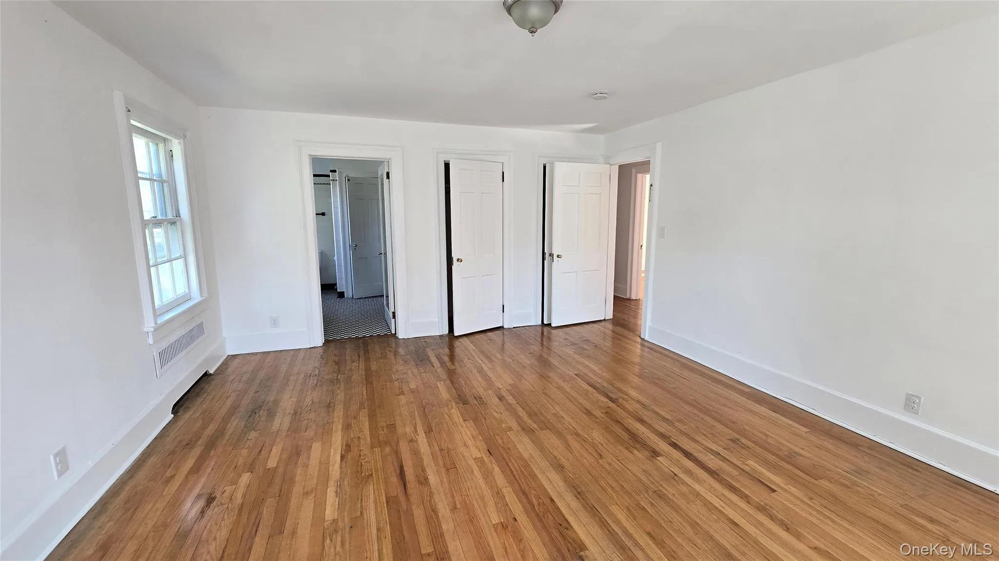 Unfurnished bedroom with wood-type flooring and ensuite bathroom Unfurnished bedroom with wood-type flooring and ensuite bathroom