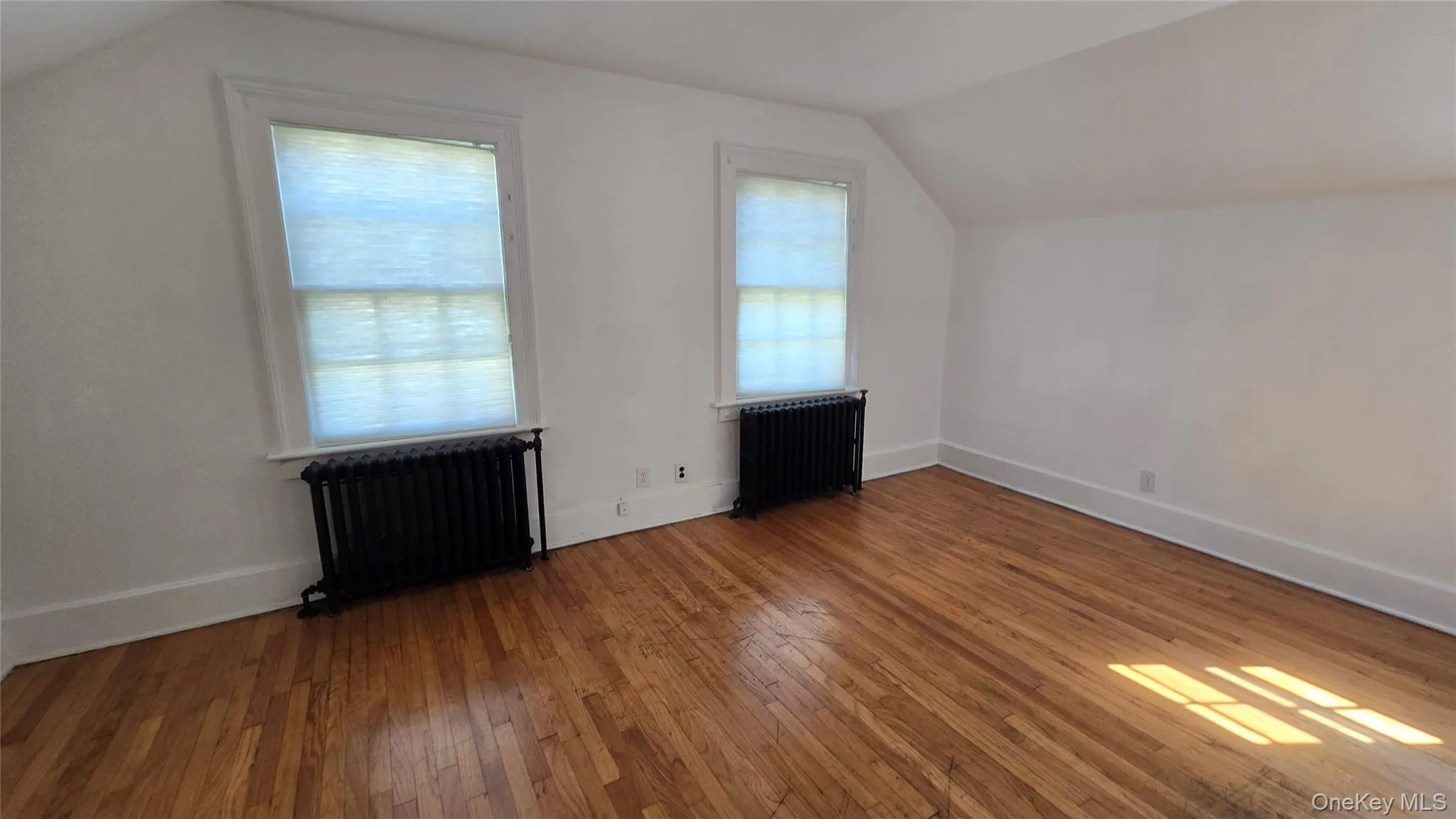 Bonus room with vaulted ceiling, radiator heating unit, and hardwood / wood-style flooring Bonus room with vaulted ceiling, radiator heating unit, and hardwood / wood-style flooring