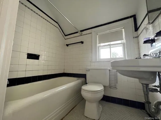 Bathroom featuring tile walls, tile patterned floors, bathtub / shower combination, and vaulted ceiling Bathroom featuring tile walls, tile patterned floors, bathtub / shower combination, and vaulted ceiling