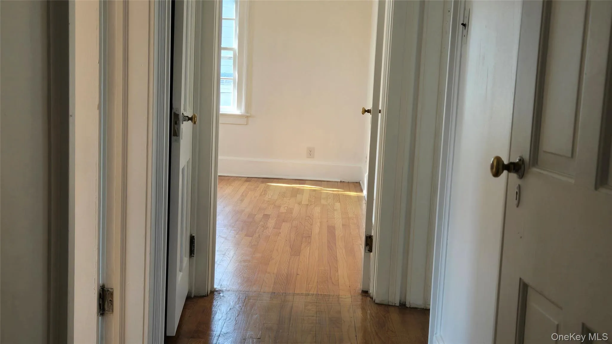 Corridor featuring dark wood-type flooring and baseboards Corridor featuring dark wood-type flooring and baseboards
