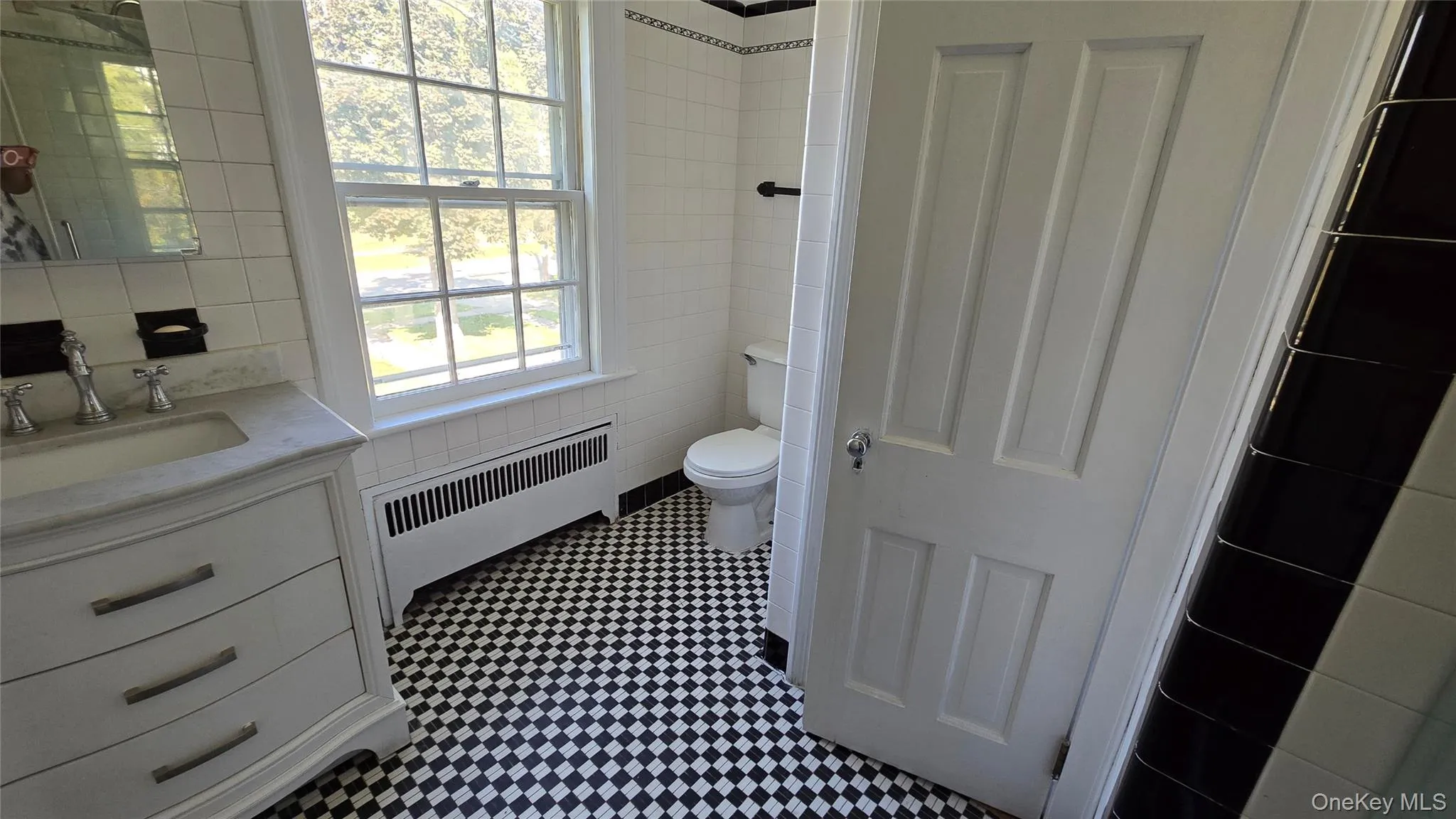 Bathroom with tile walls, vanity, and radiator heating unit Bathroom with tile walls, vanity, and radiator heating unit