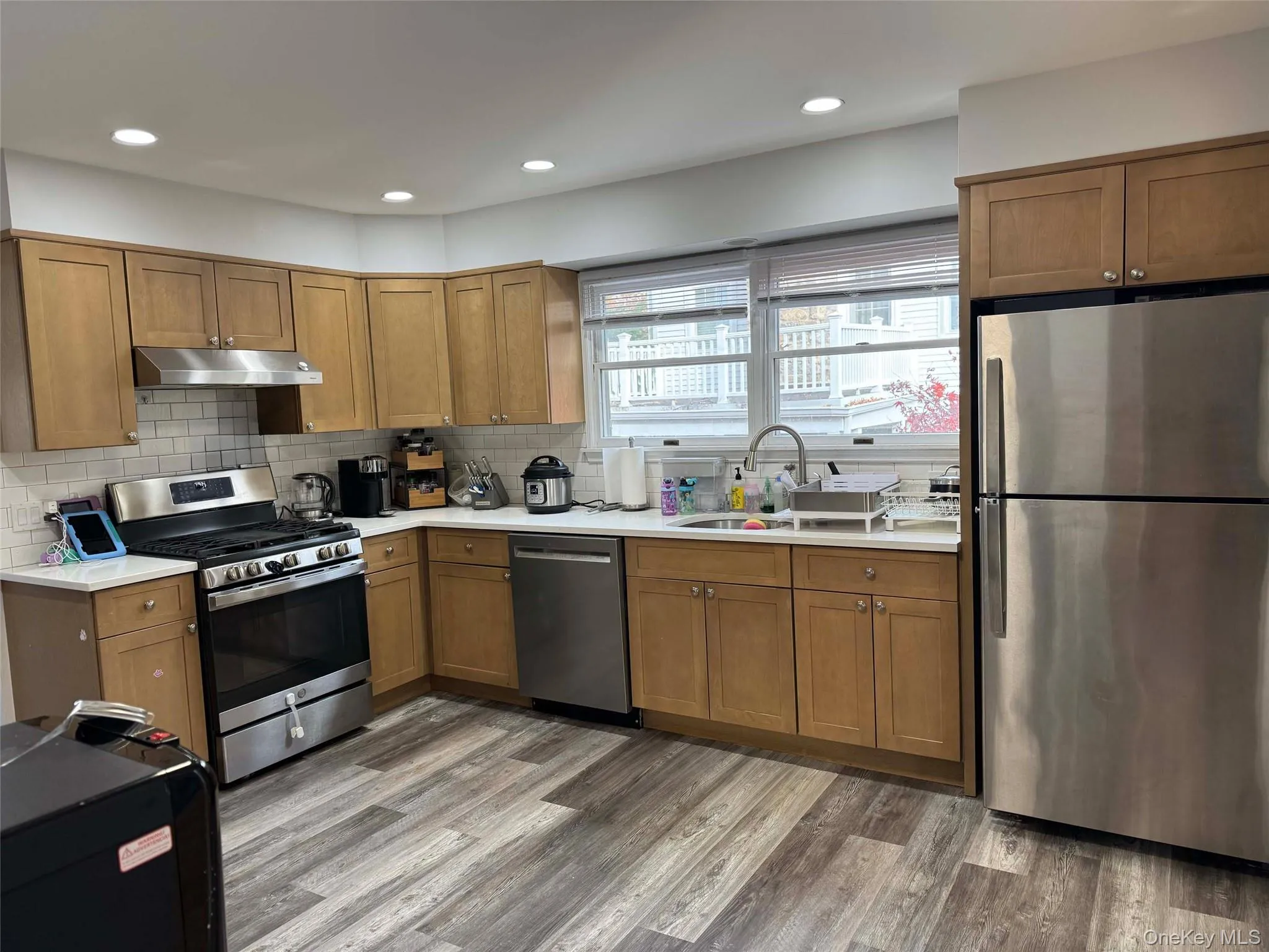 Kitchen featuring appliances with stainless steel finishes, brown cabinetry, tasteful backsplash, and recessed lighting Kitchen featuring appliances with stainless steel finishes, brown cabinetry, tasteful backsplash, and recessed lighting