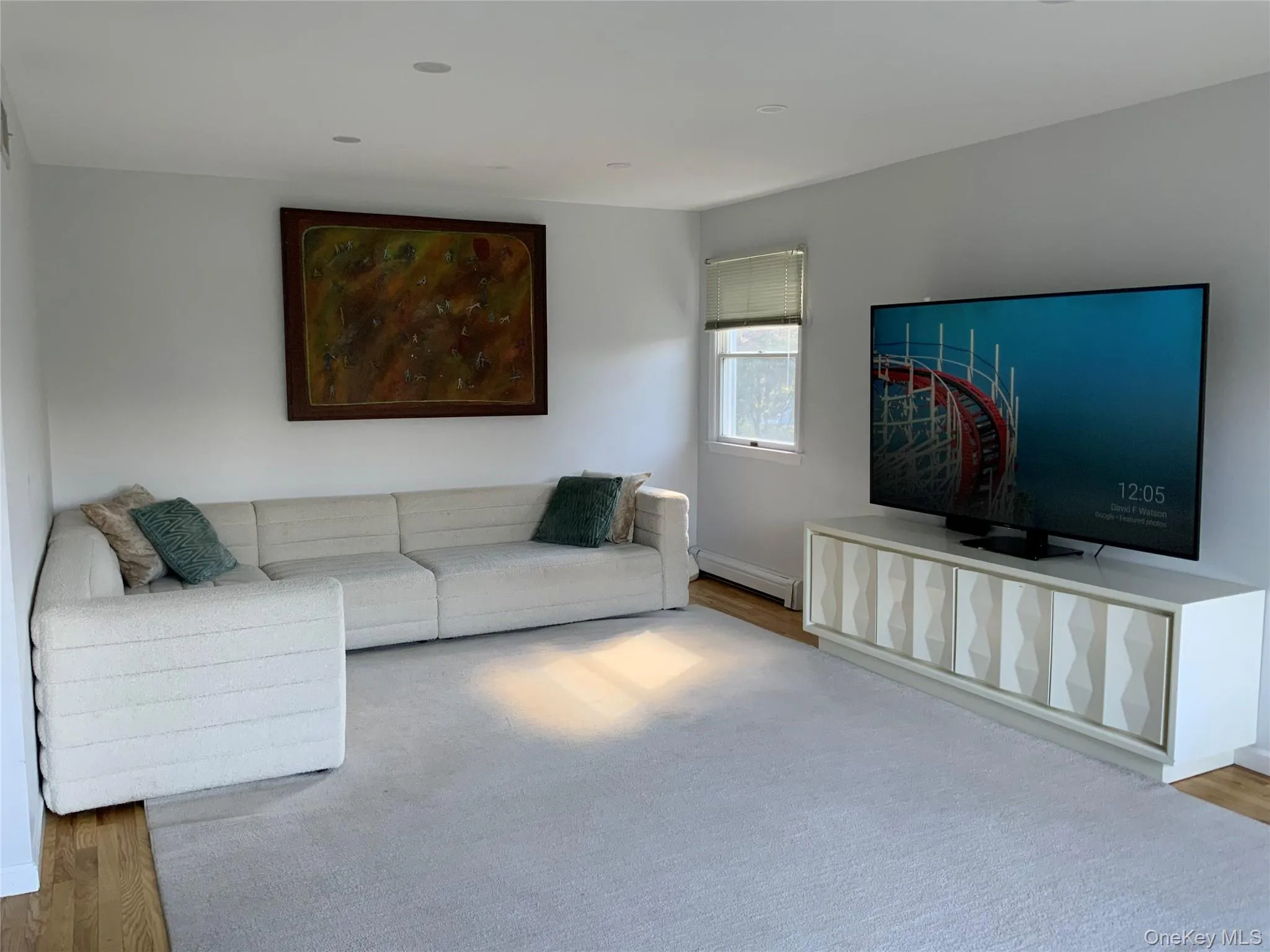 Unfurnished living room featuring wood finished floors and a baseboard radiator Unfurnished living room featuring wood finished floors and a baseboard radiator