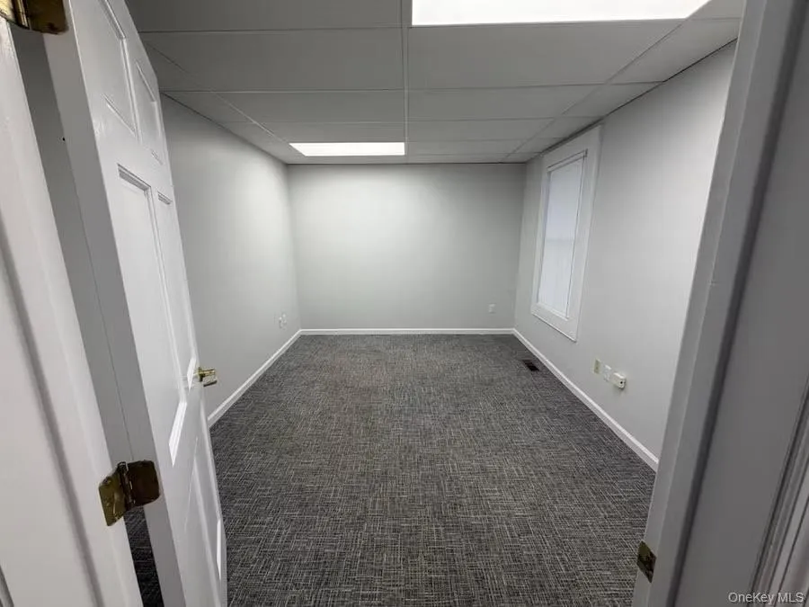 Spare room featuring dark carpet and a drop ceiling Spare room featuring dark carpet and a drop ceiling