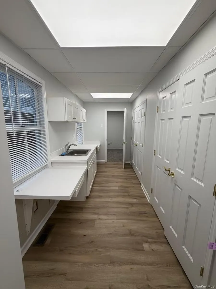 Kitchen featuring light countertops, white cabinetry, a drop ceiling, and dark wood-style floors Kitchen featuring light countertops, white cabinetry, a drop ceiling, and dark wood-style floors