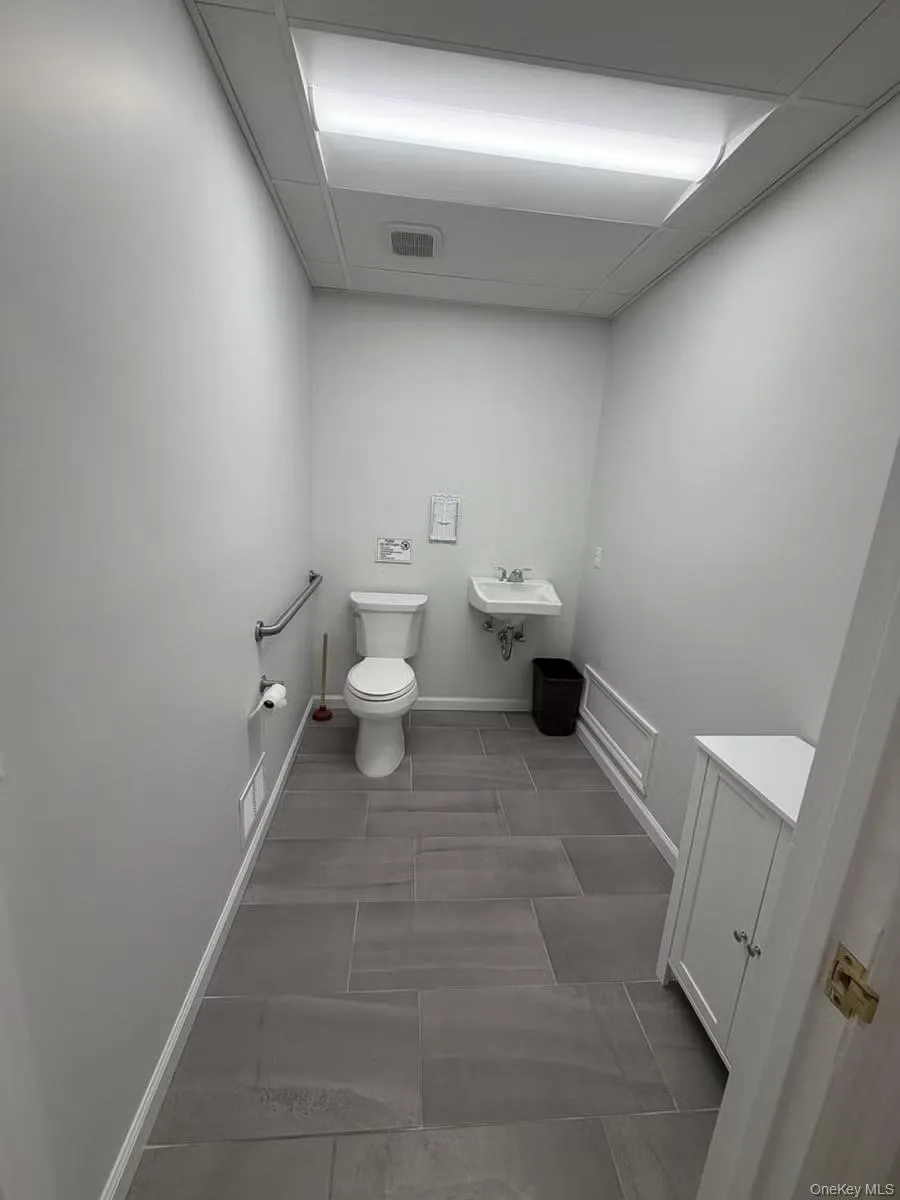 Half bathroom featuring toilet and a drop ceiling Half bathroom featuring toilet and a drop ceiling