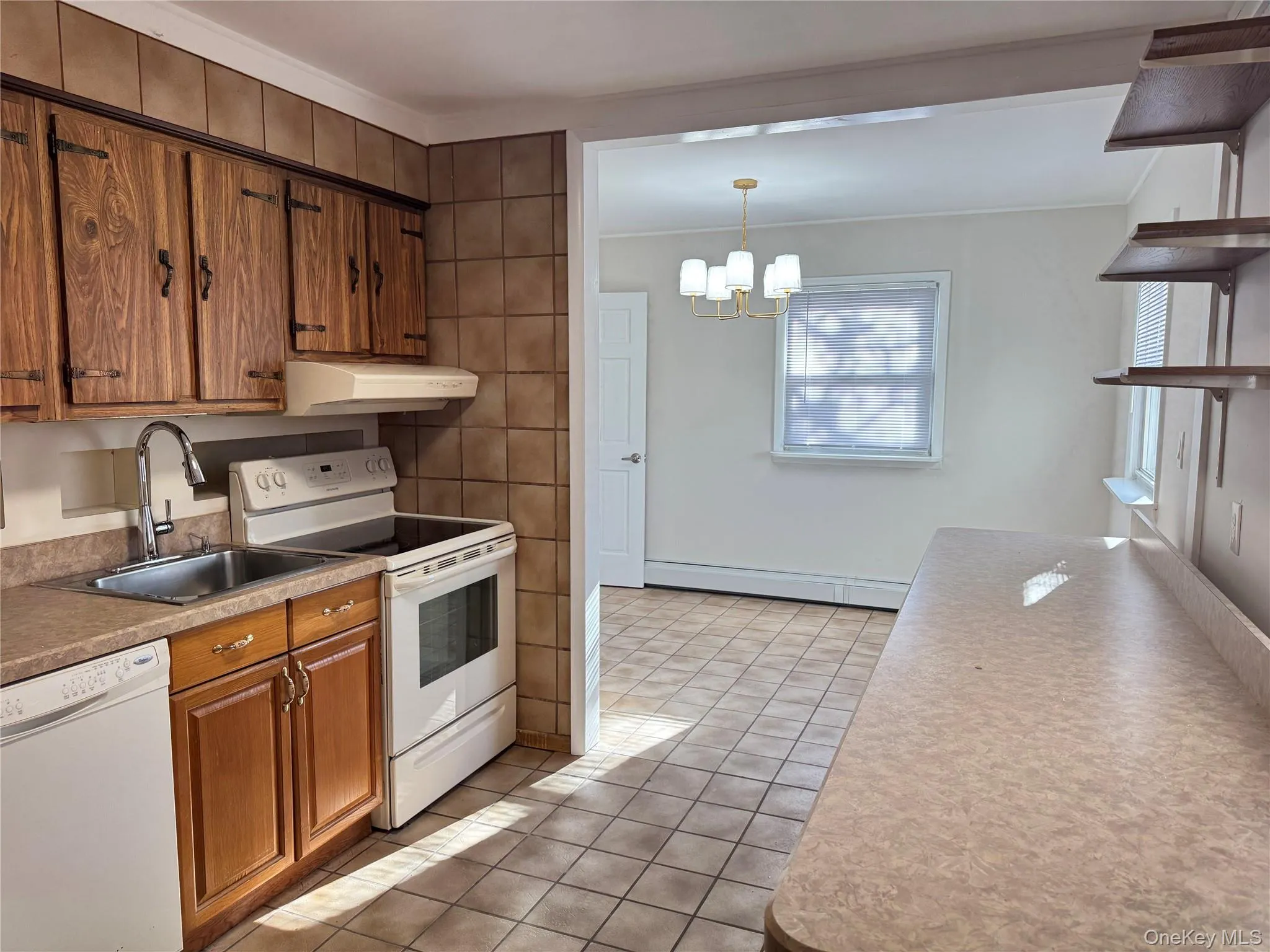 Kitchen with white appliances, brown cabinets, open shelves, light tile patterned flooring, and baseboard heating Kitchen with white appliances, brown cabinets, open shelves, light tile patterned flooring, and baseboard heating