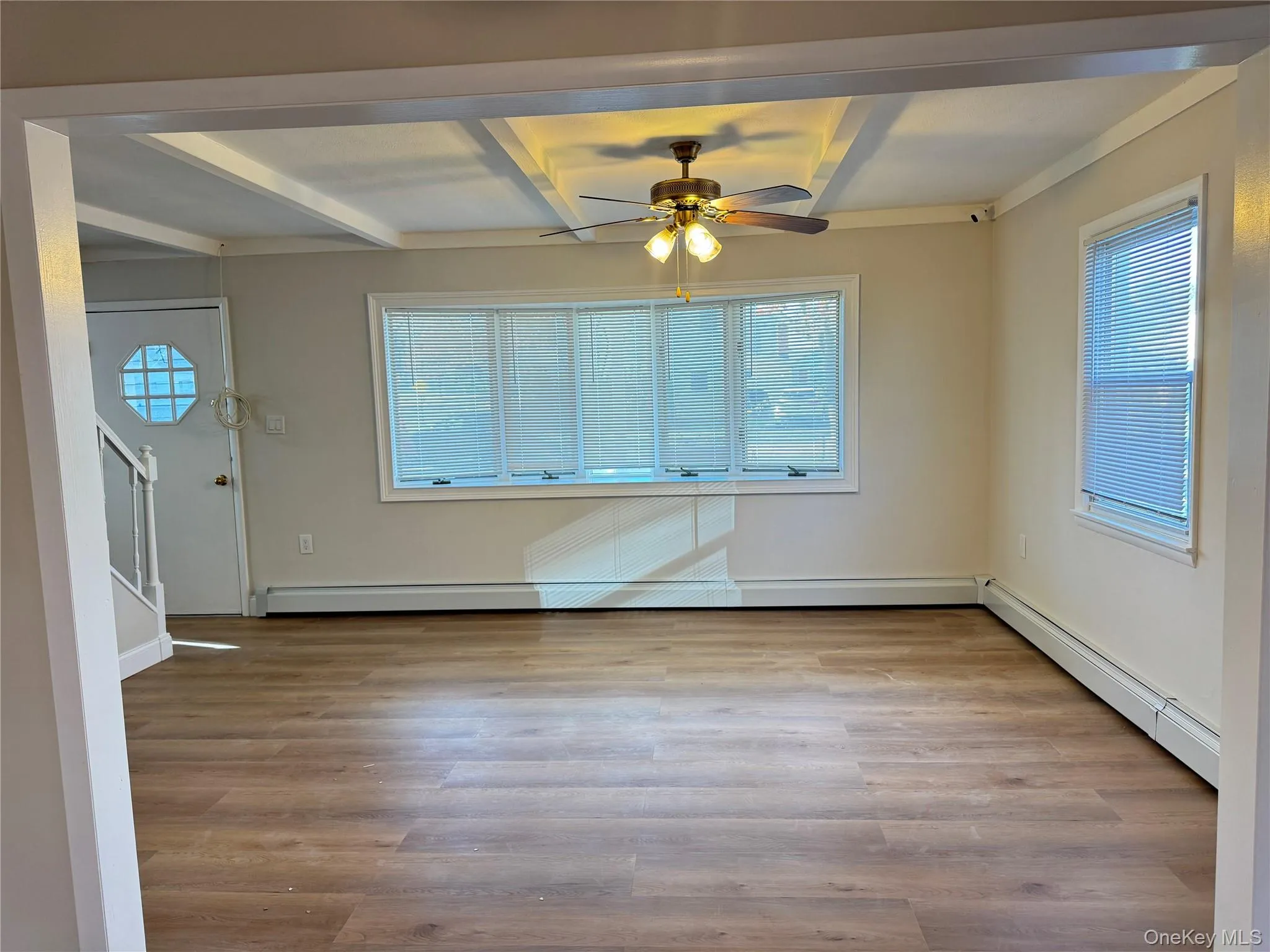 Unfurnished dining area with a baseboard heating unit, light wood-style floors, beam ceiling, coffered ceiling, and ornamental molding Unfurnished dining area with a baseboard heating unit, light wood-style floors, beam ceiling, coffered ceiling, and ornamental molding