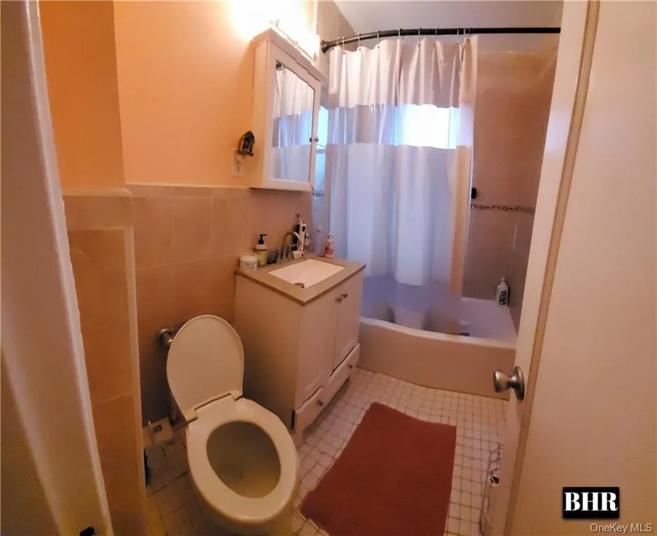 Full bath with shower / bath combination with curtain, vanity, and tile walls Full bath with shower / bath combination with curtain, vanity, and tile walls