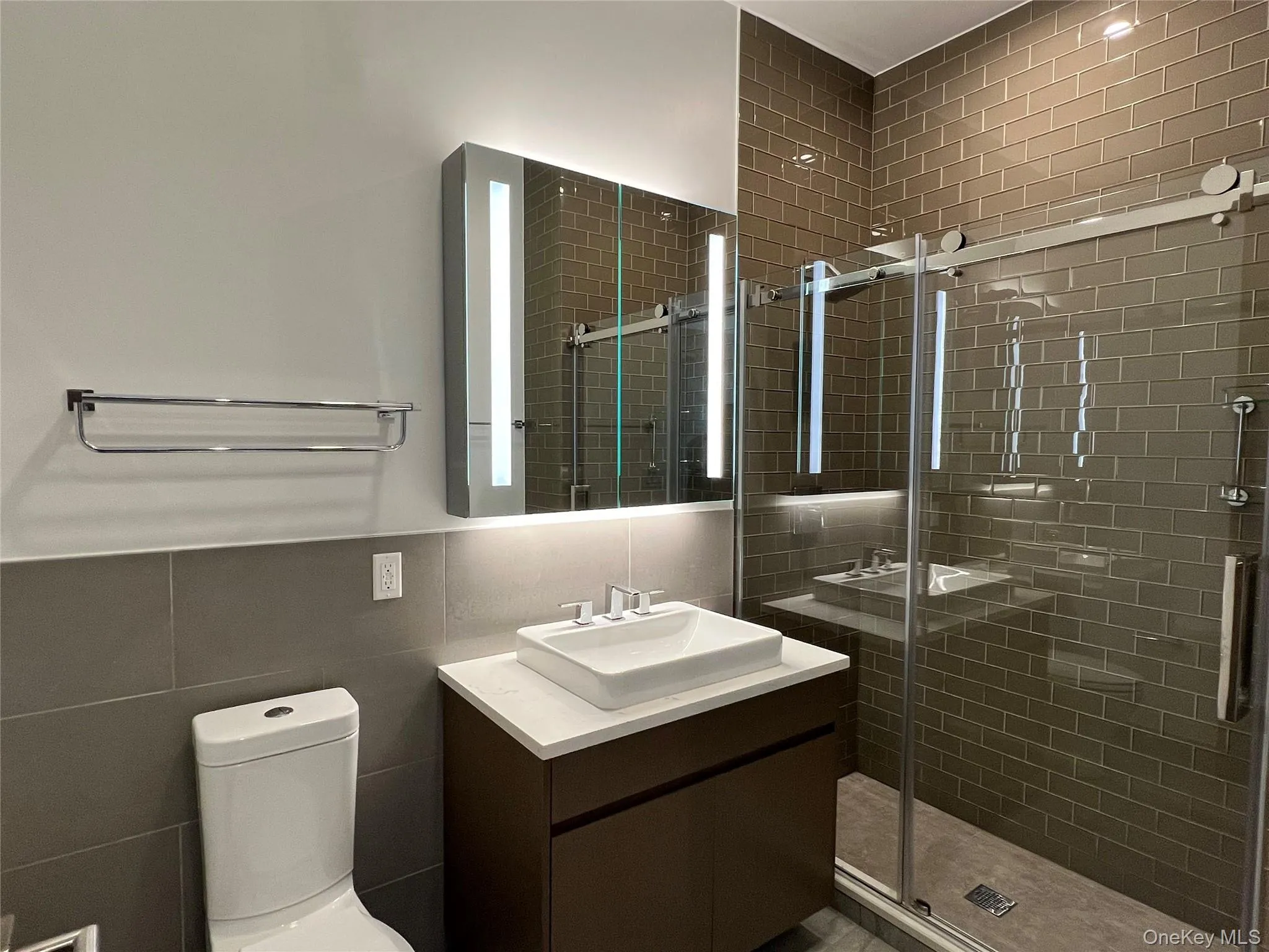 Full bathroom with tile walls, vanity, and a stall shower Full bathroom with tile walls, vanity, and a stall shower