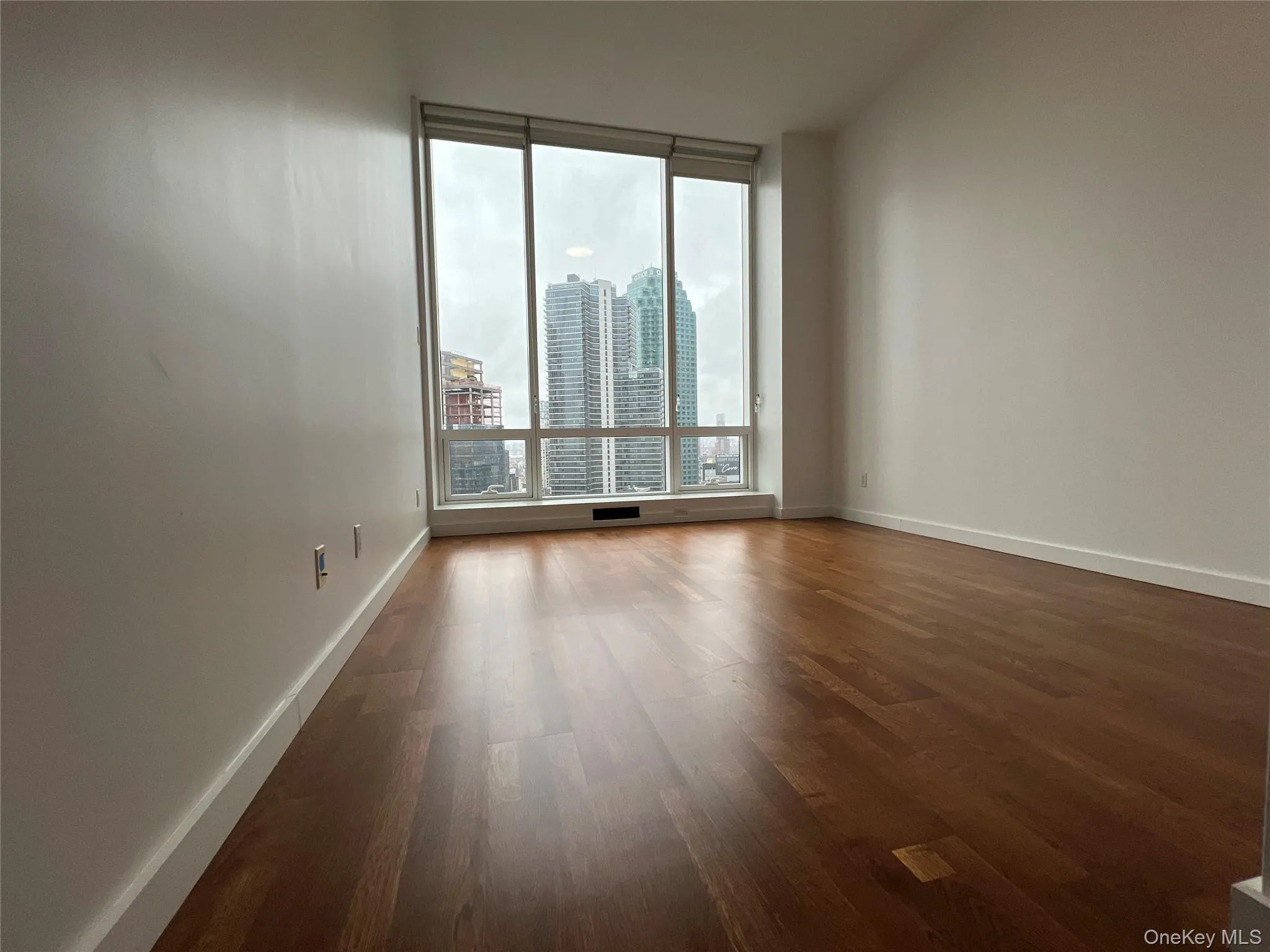 Empty room with dark wood-type flooring and a city view Empty room with dark wood-type flooring and a city view