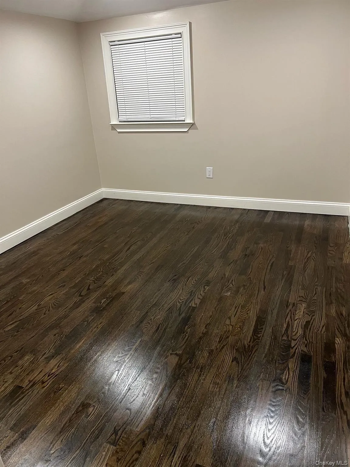 Spare room with dark wood finished floors and baseboards Spare room with dark wood finished floors and baseboards